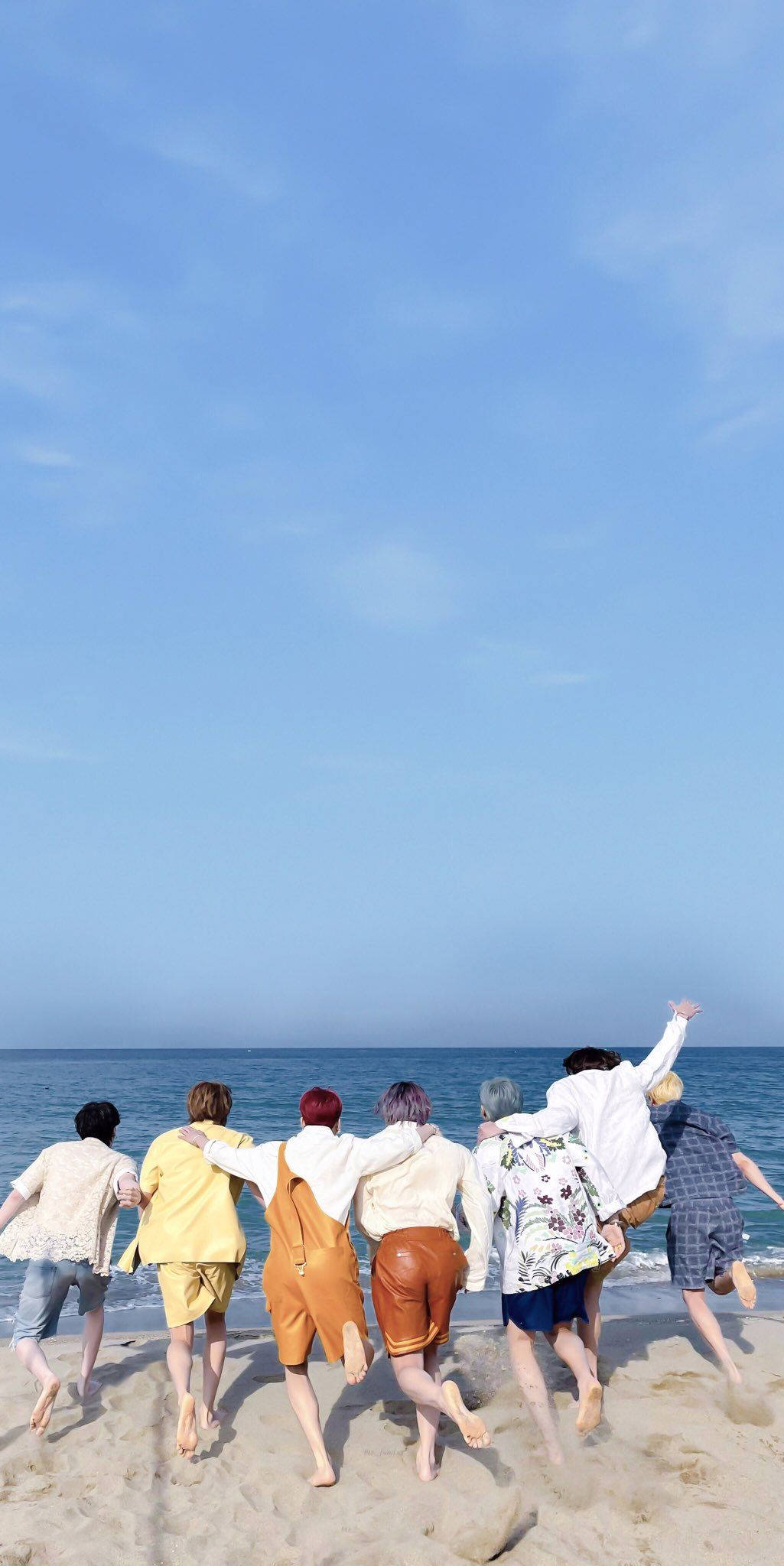 BTS 美學 桌布 壁紙 — 七個人在沙灘上赤腳奔跑，朝著清澈藍天下的海洋前進。