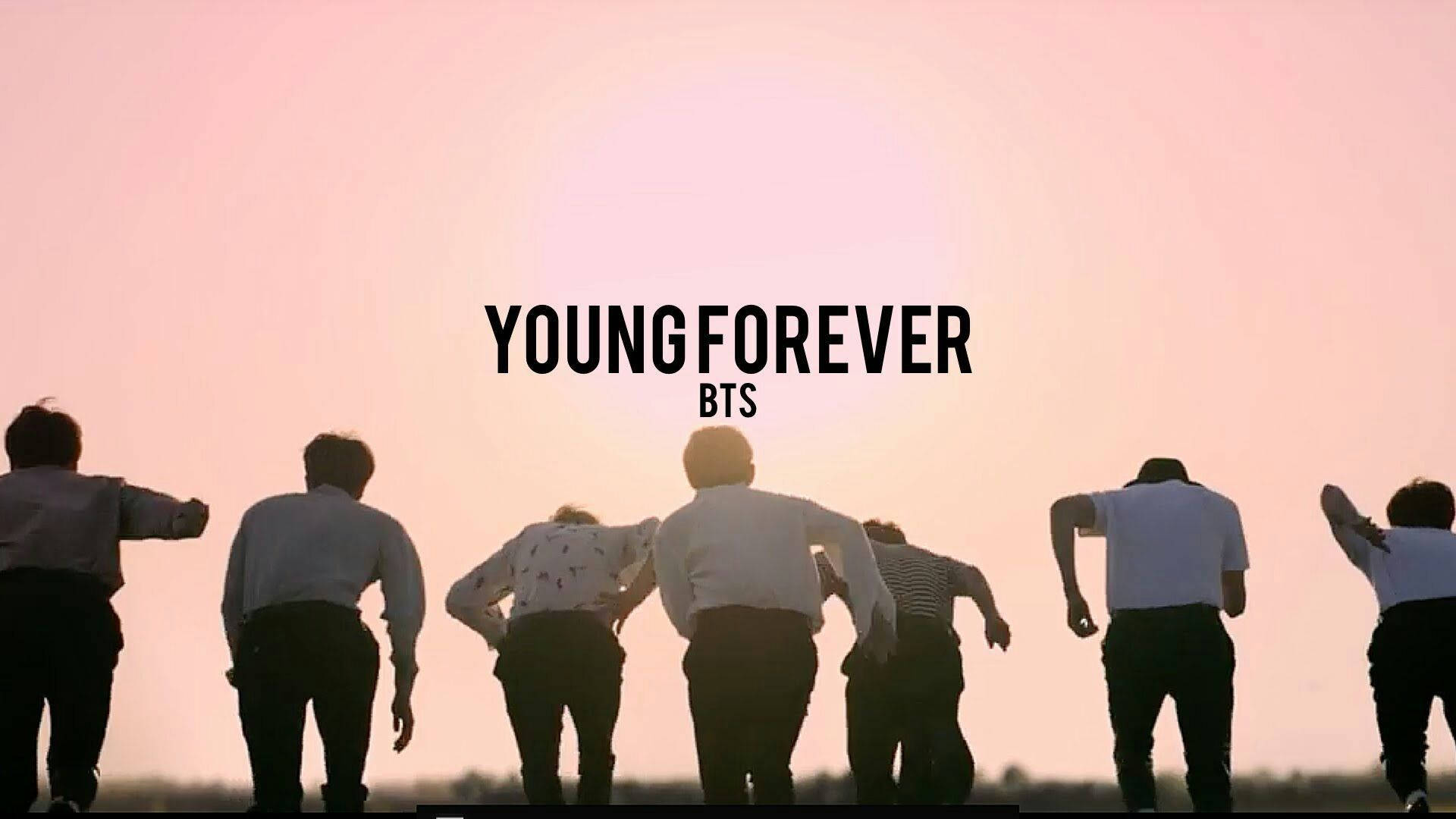 BTS 桌布 壁紙 — 七個剪影人物背光站立在發光的粉紅色日落前，並有粗體文字 YOUNGFOREVER BTS。