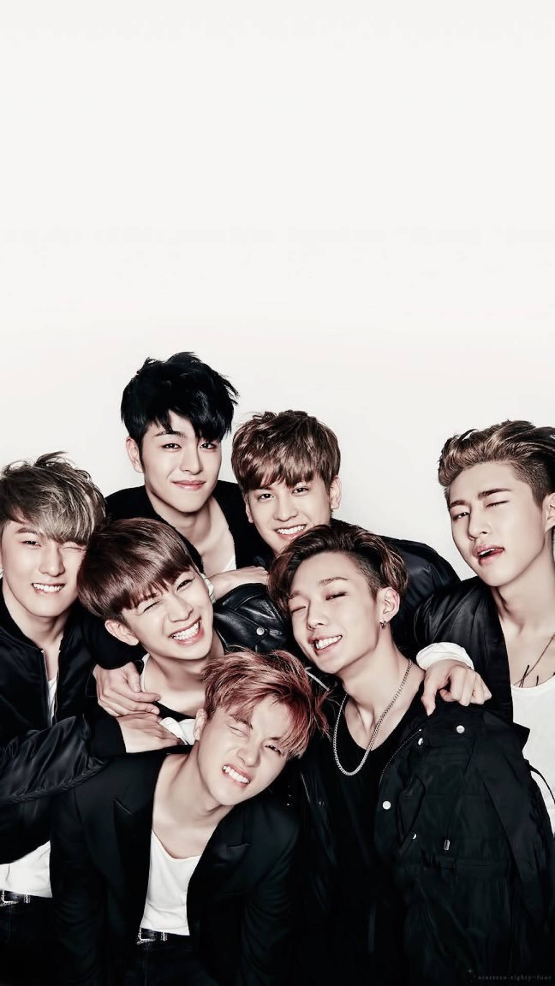 Ikon 桌布 壁紙 — 七個微笑的年輕男子穿著黑色外套，在純白背景前緊密地擺出俏皮的表情。