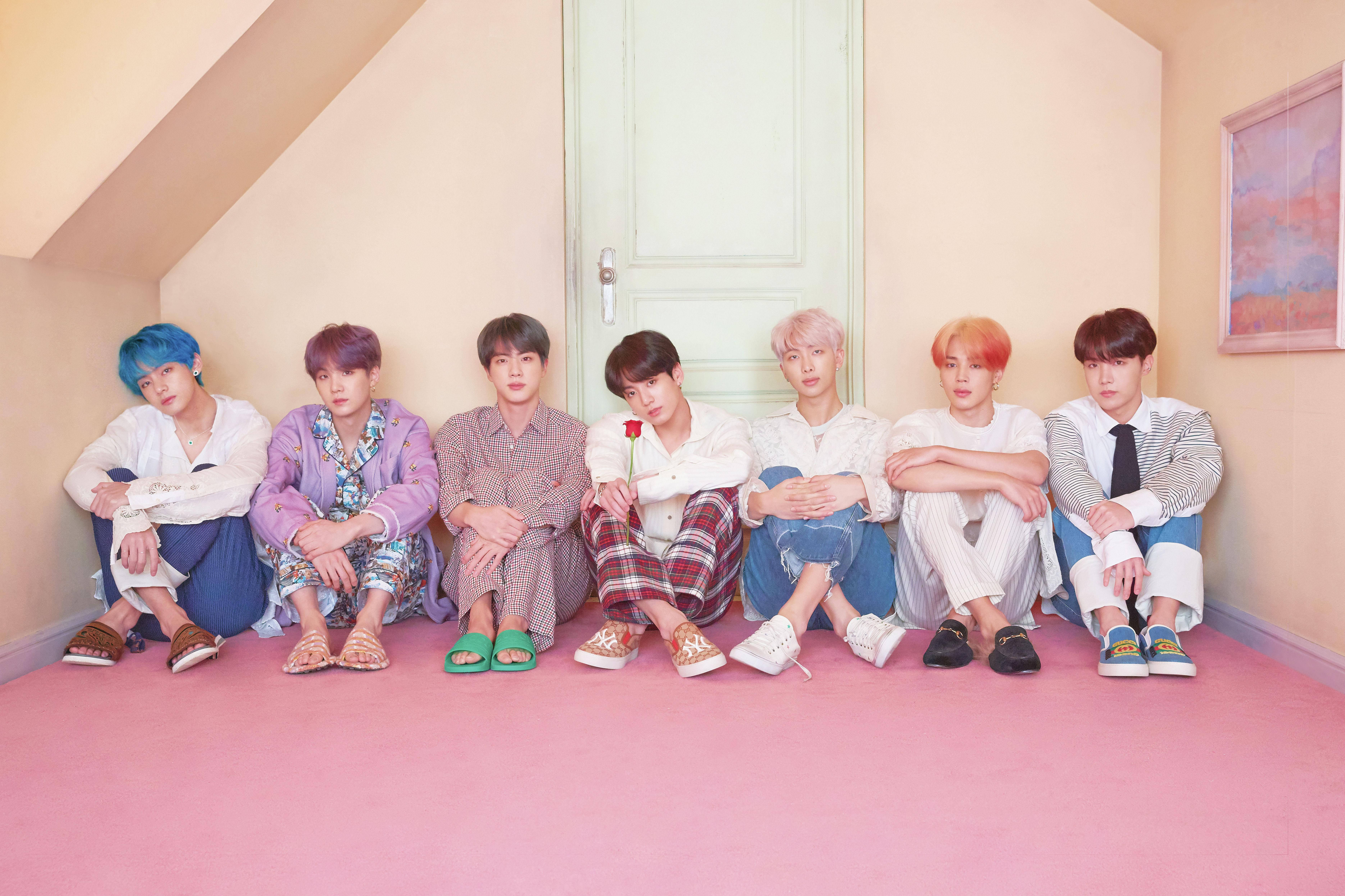 BTS 桌布 桌布 壁紙 — 七個有彩色頭髮的年輕男人隨意地坐在粉紅色地板的柔和色調閣樓房裡。