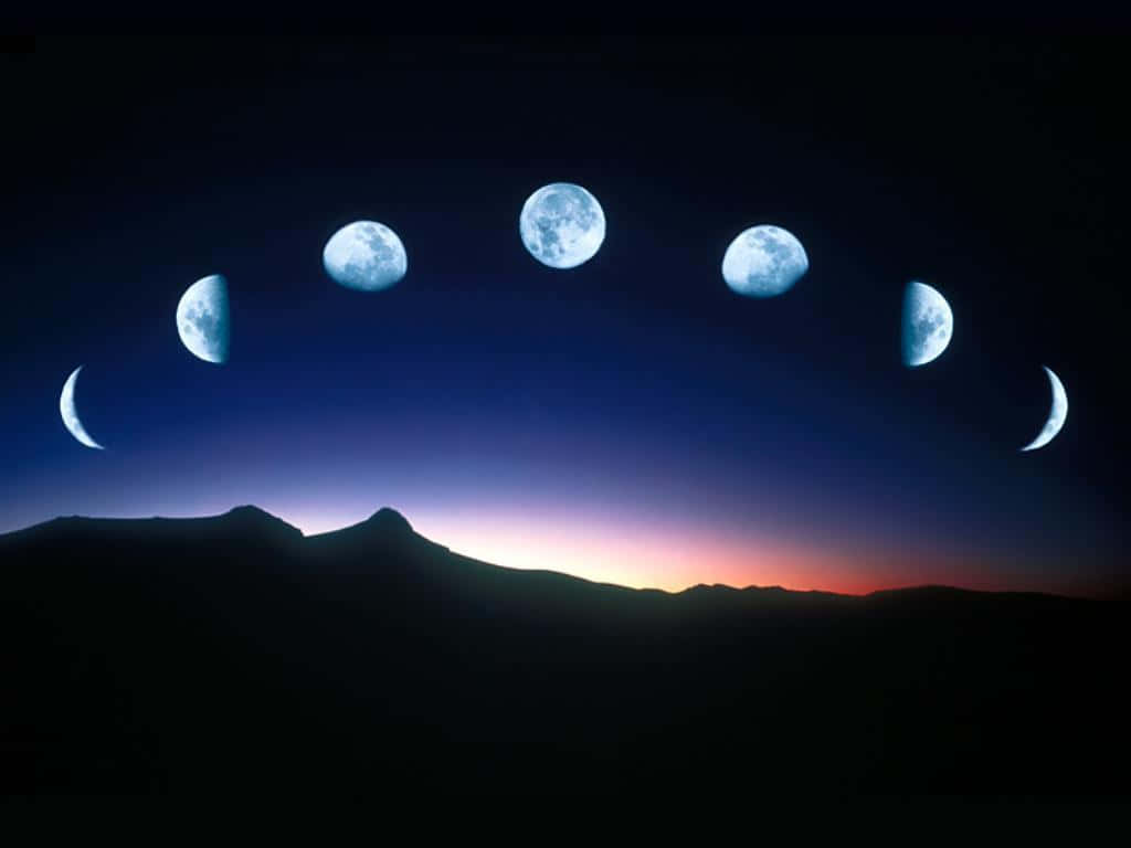 Moon Phases 桌布 壁紙 — 七個發光藍色月亮在不同相位拱起，在暮色中越過黑暗的山脈輪廓。