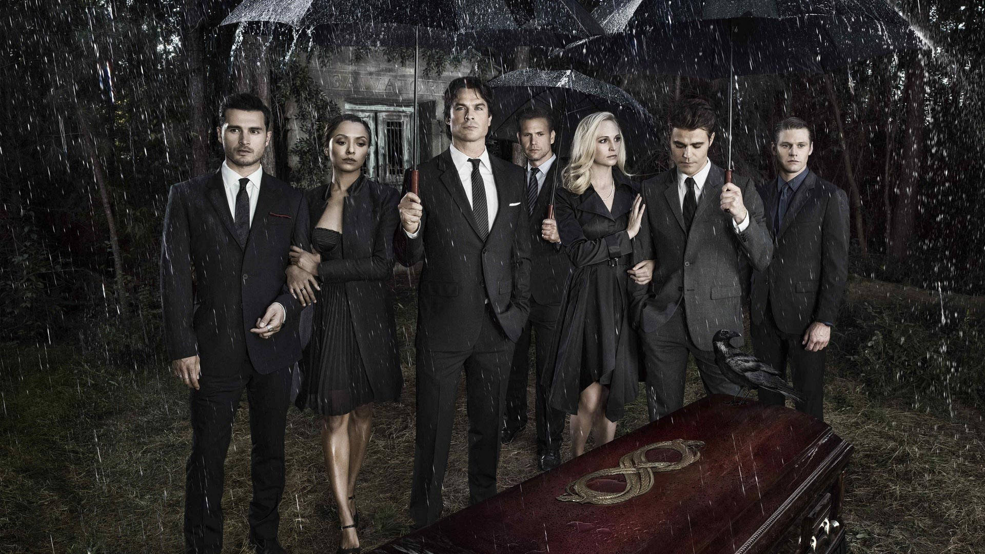 Vampire Diaries 桌布 壁紙 — 七個衣著優雅的人物在雨濕的墓地中撐著傘，莊嚴地站在一個華麗的棺材旁邊。