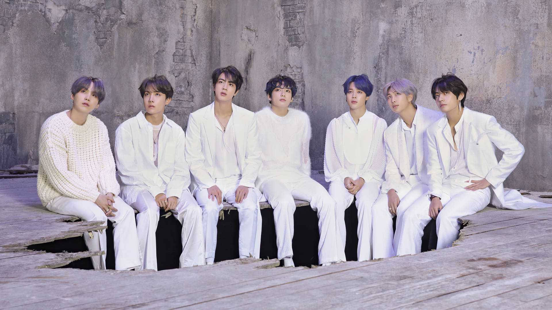 BTS 桌布 壁紙 — 七個身穿白色服裝的男人坐在木製平台上，背景是風化的混凝土牆。