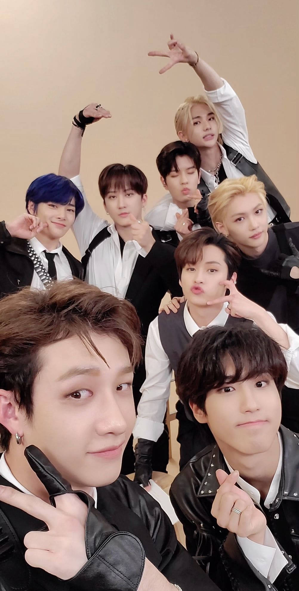 Stray Kids 桌布 壁紙 — 七名年輕男子穿著時尚的黑白服裝，在純米色牆前頑皮地擺出和平手勢。