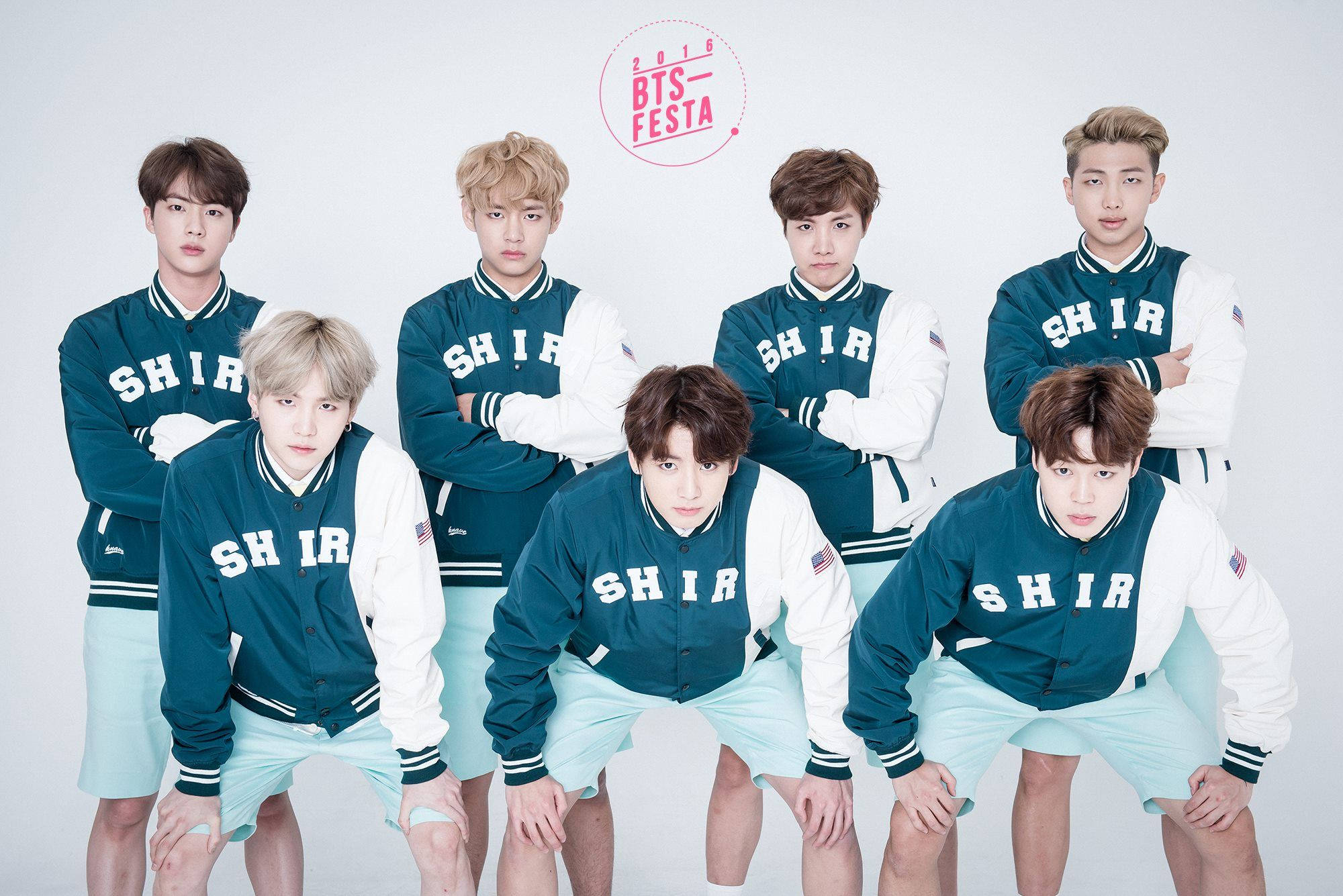 BTS 桌布 壁紙 — 七名年輕男子身穿相配的綠色和白色大學夾克，在純白色背景前自信地擺姿勢。