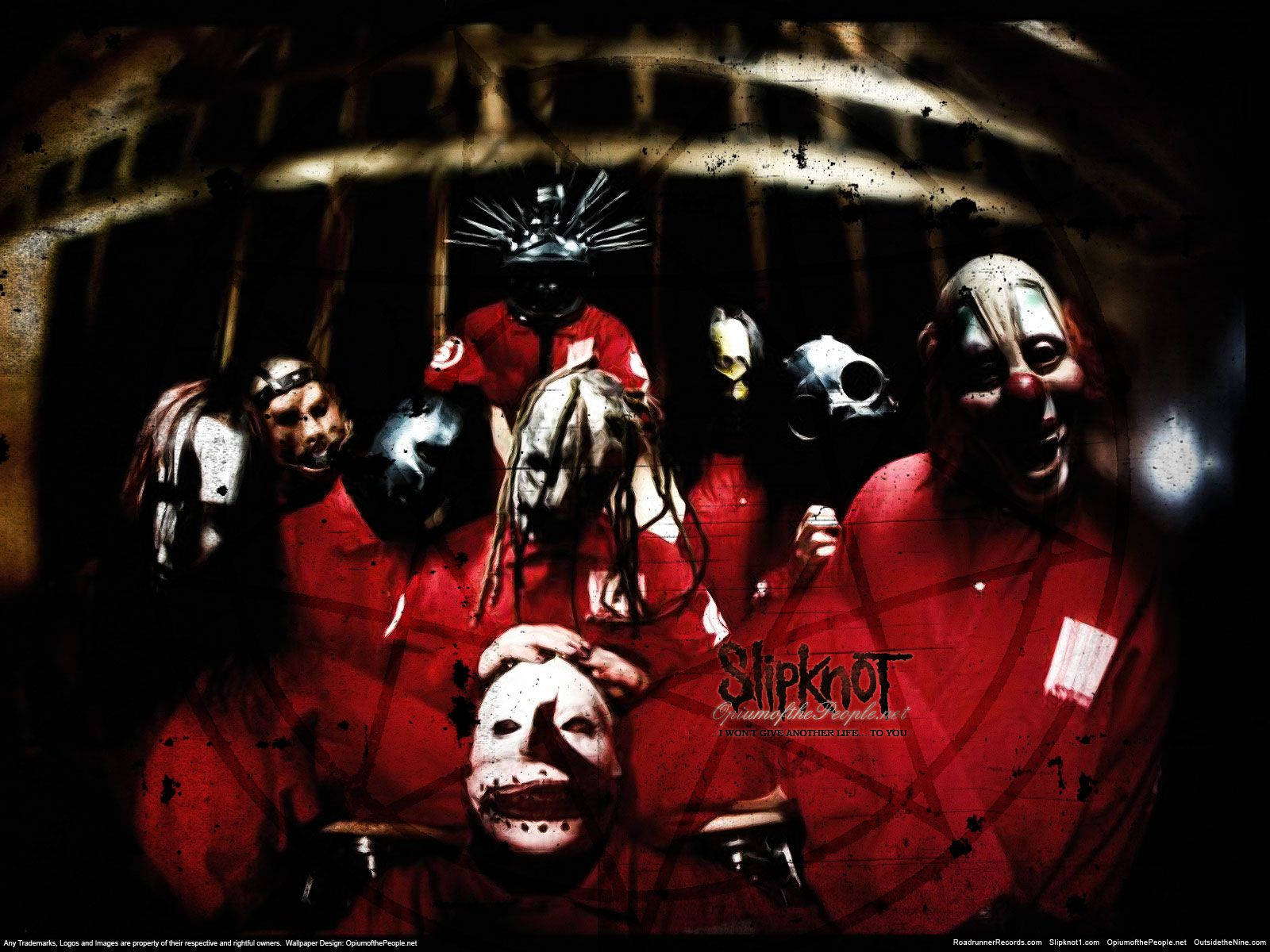 Slipknot 桌布 壁紙 — 七名戴面具的樂隊成員身穿紅色連身衣，在黑暗、粗獷、籠子般的環境中，在戲劇性的燈光下威風凜凜地站立。