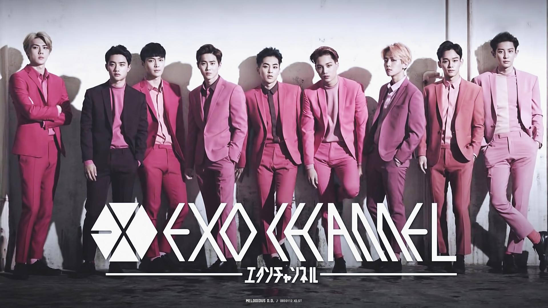 K-pop 桌布 壁紙 — 七名身穿協調粉紅色西裝的男子自信地靠著素牆擺姿勢，下方有粗體白色品牌標誌。
