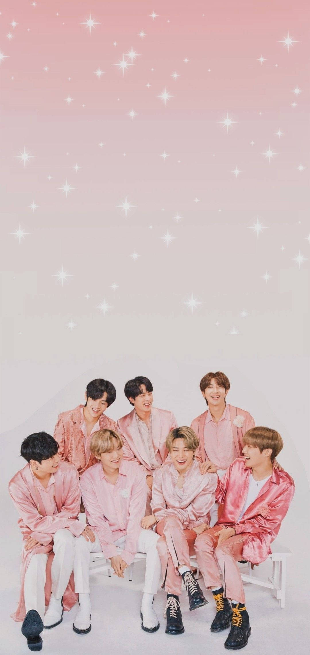 BTS 桌布 壁紙 — 七名身穿粉紅色緞面服裝的年輕男子一起坐在白色長椅上，頭頂是閃爍的粉紅色天空。