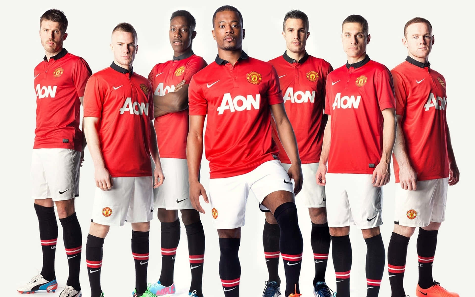 Manchester United Team 桌布 壁紙 — 七名身穿紅色曼聯球衣的足球運動員在純白色背景前自信地擺姿勢。