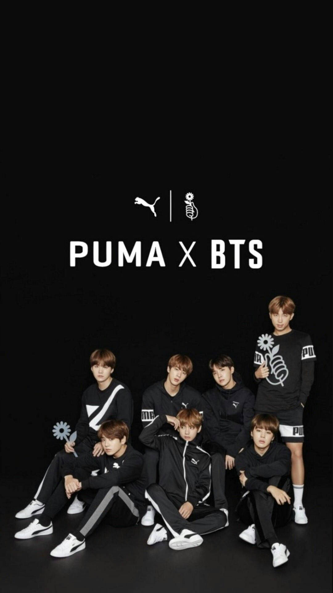 Puma 桌布 壁紙 — 七名身穿黑色 Puma 運動服的年輕男性在帶有白色標誌文字的純黑色背景前自信地擺姿勢。