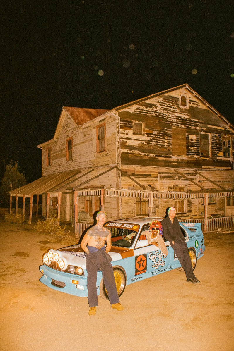 Travis Scott Aesthetic 桌布 壁紙 — 三人在星空下自信地站在一輛復古賽車旁，背景是一間破舊的木屋。