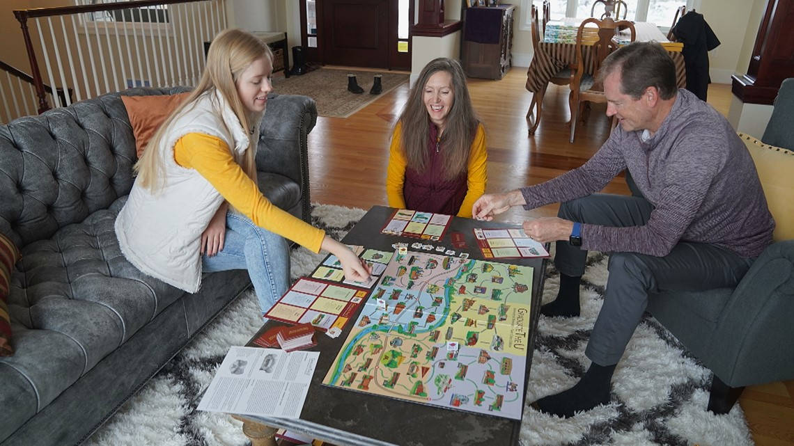 game 桌布 壁紙 — 三人在舒適的客廳裡圍著咖啡桌大笑並玩色彩繽紛的棋盤遊戲。