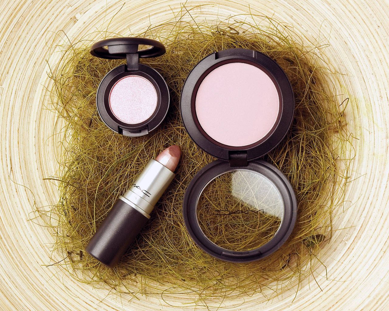 Makeup 桌布 壁紙 — 三件MAC化妝品放在一個鋪有乾草的編織籃子裡，展現柔和的粉紅色和閃爍光澤。