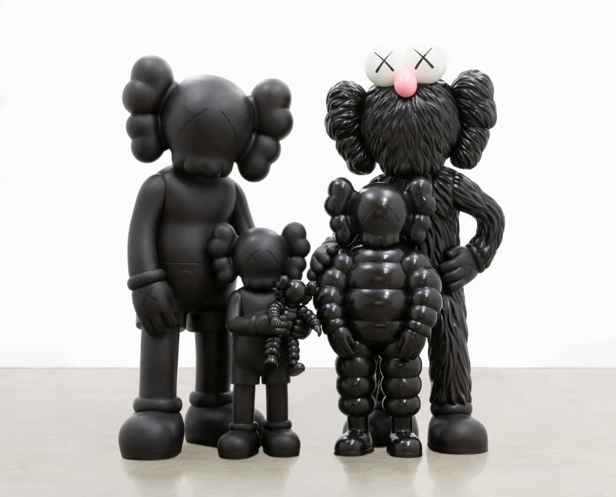 KAWS 桌布 壁紙 — 三件光澤黑色KAWS雕塑，帶有交叉的眼窩，一起站在淺色地板上，背景是白色牆壁。