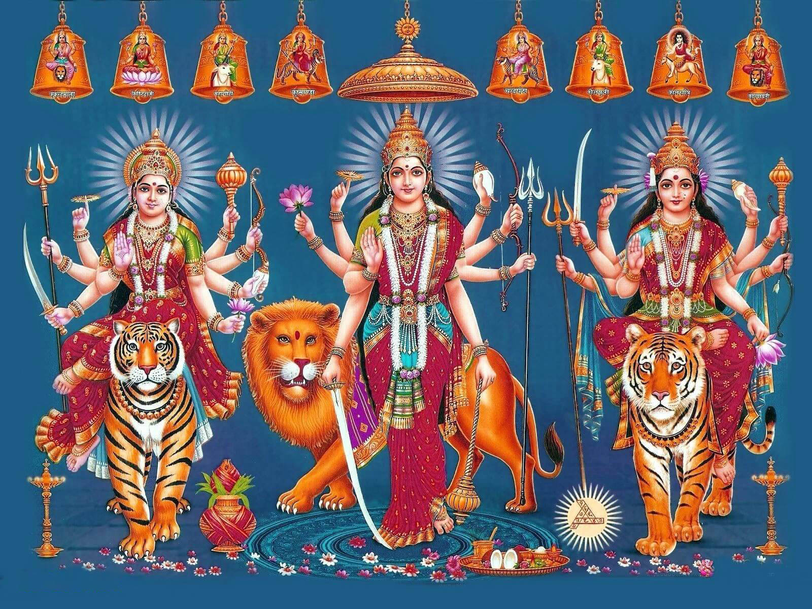 Mata Rani 桌布 壁紙 — 三位光芒四射、多臂的印度教女神，身著紅金服飾，坐在老虎和獅子上，背景為深藍色，掛有鈴鐺。