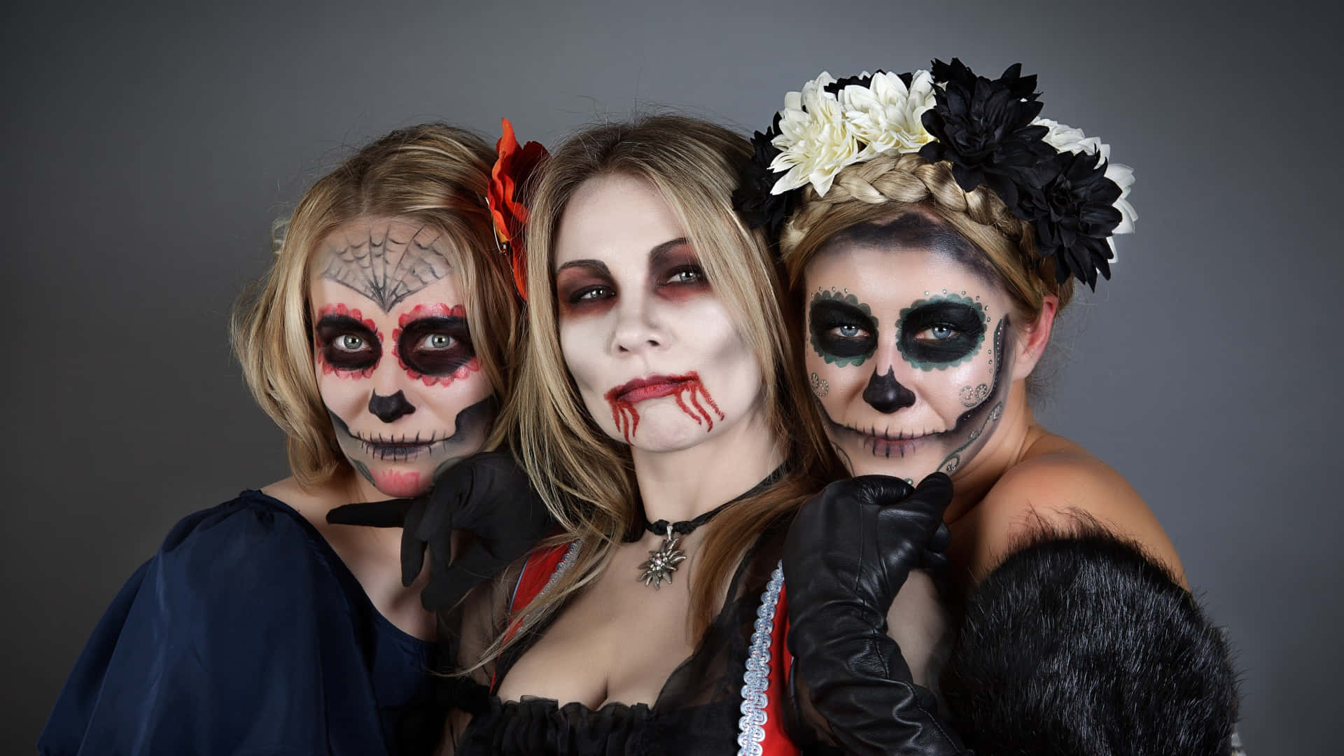 Horror Costumes 桌布 壁紙 — 三位化著精緻糖骷髏妝容的女性，在純灰色背景前緊密地擺姿勢。
