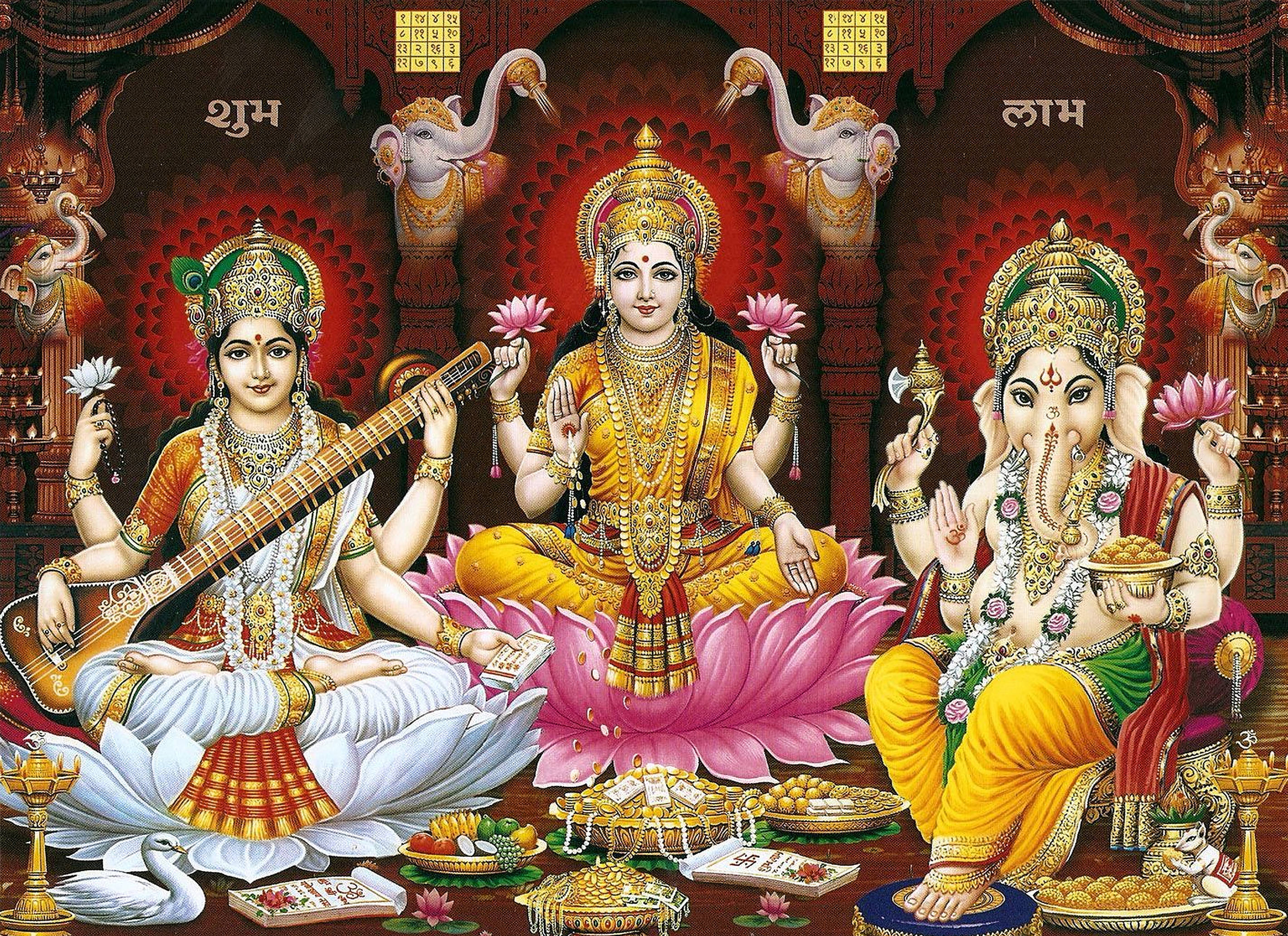 laxmi ganesh saraswati 桌布 壁紙 — 三位印度教神祇端坐在裝飾著珠寶和供品的蓮花上，置身於裝飾華麗的寺廟環境中。