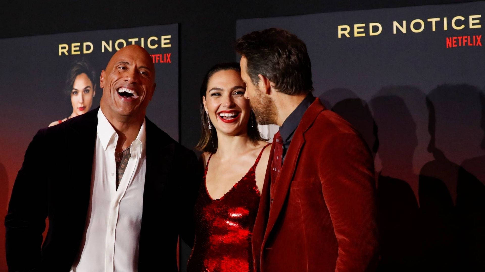 Notice 桌布 壁紙 — 三位名人在Red Notice Netflix首映會上一起大笑，背後有電影海報。