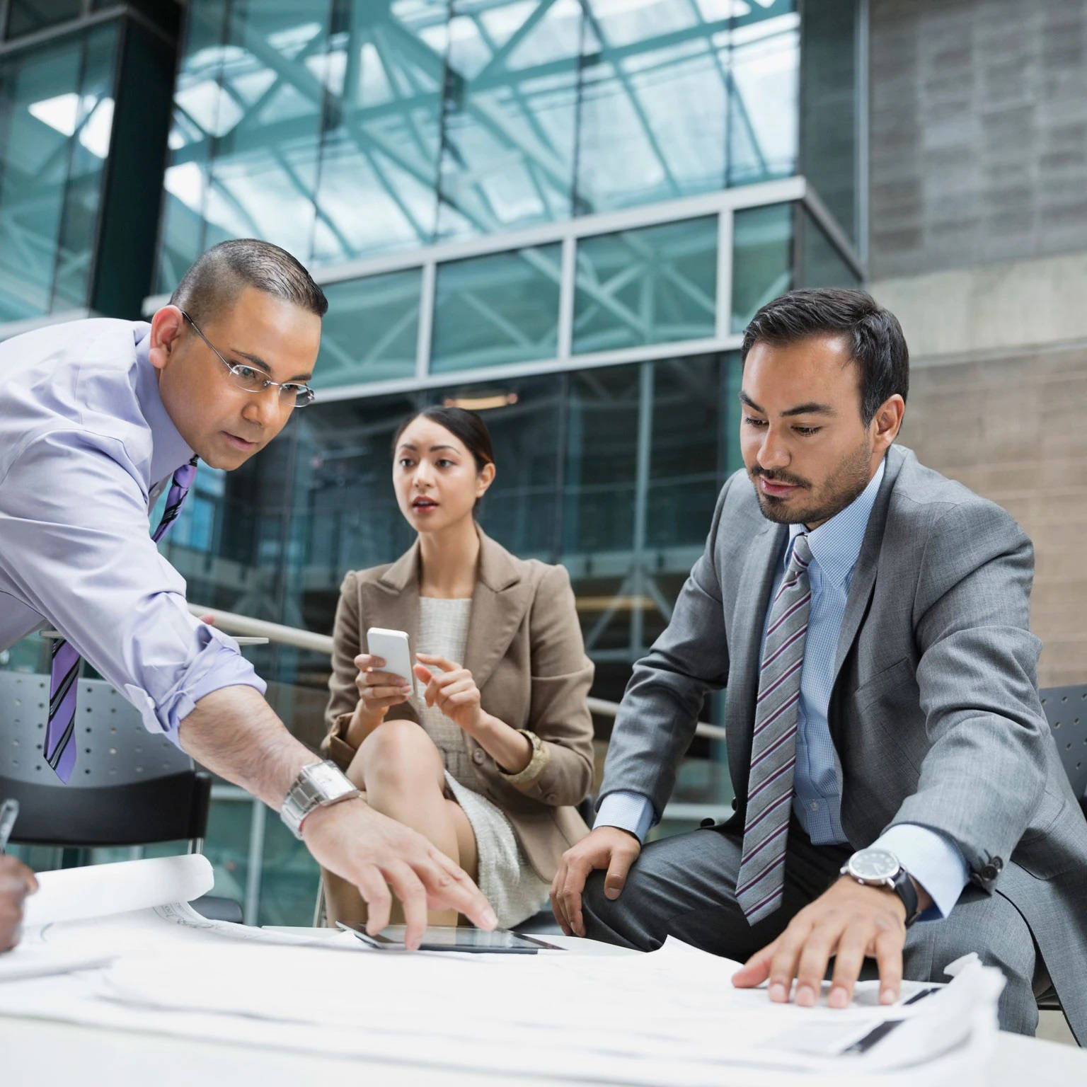 Teamwork 桌布 壁紙 — 三位商業專業人士在現代玻璃牆辦公室空間的桌子周圍緊密合作。