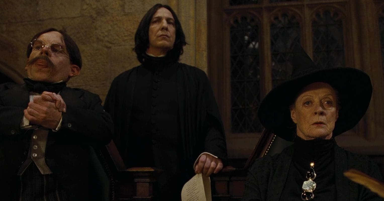 The Hogwarts Professors 桌布 壁紙 — 三位嚴肅的霍格華茲教授站在光線昏暗的石廳中，廳內有哥德式窗戶和華麗的木製品。