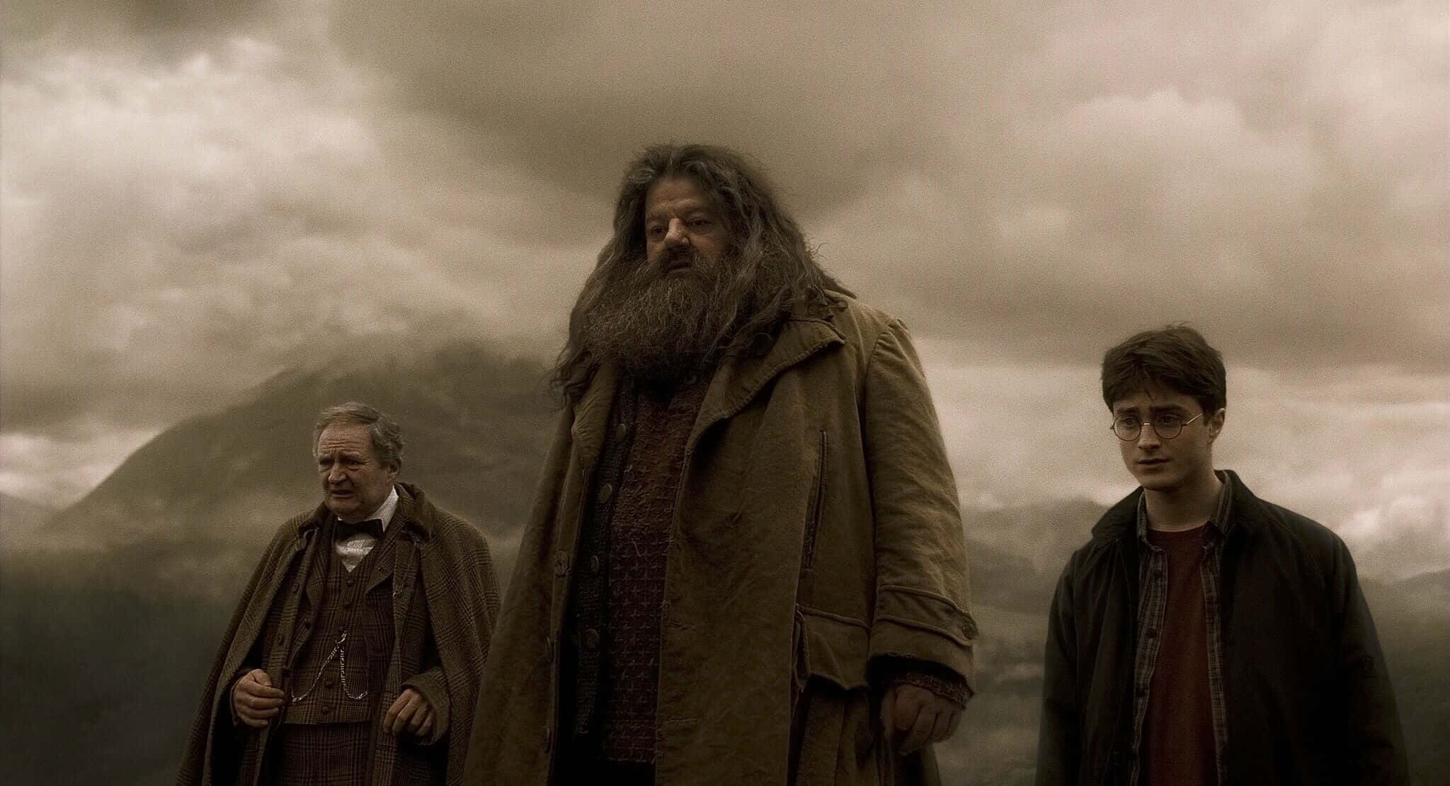 Harry Potter Landscape 桌布 壁紙 — 三位巫師莊嚴地站在霧氣瀰漫的山脊上，天空陰沉密佈。