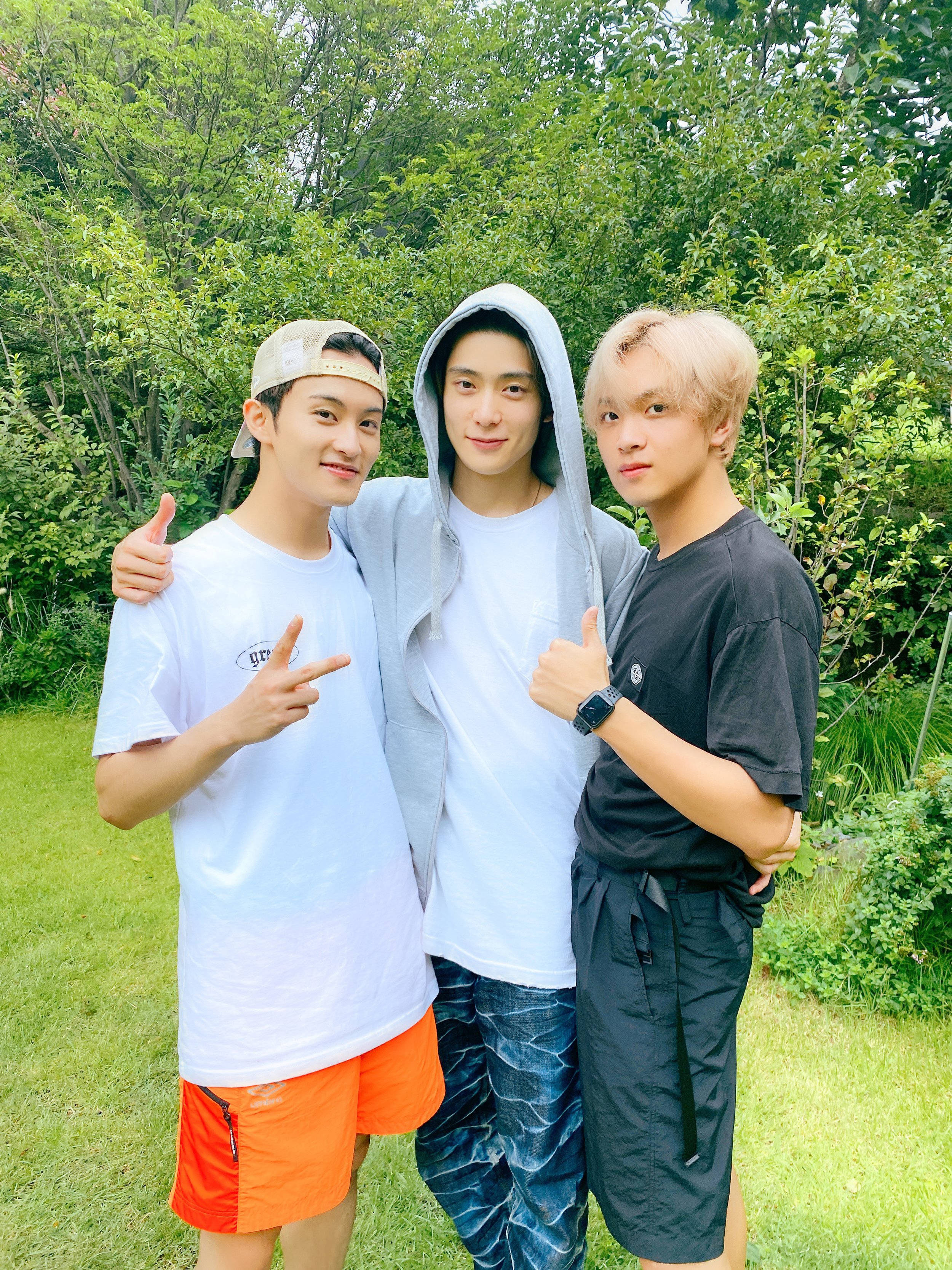 Nct 桌布 壁紙 — 三位年輕男子在翠綠花園中開心擺姿勢，互相摟著對方並豎起大拇指。