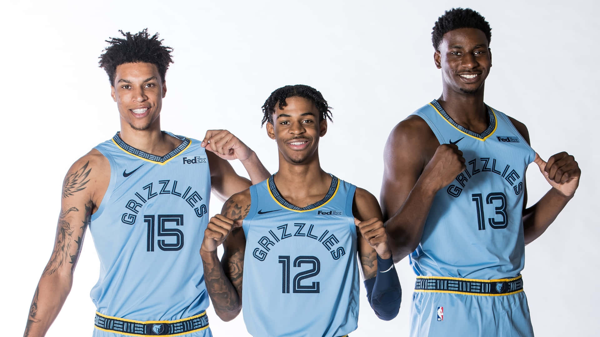 Memphis Grizzlies 桌布 壁紙 — 三位微笑的曼菲斯灰熊隊籃球運動員身穿淺藍色球衣，在純白背景前自信地擺姿勢。