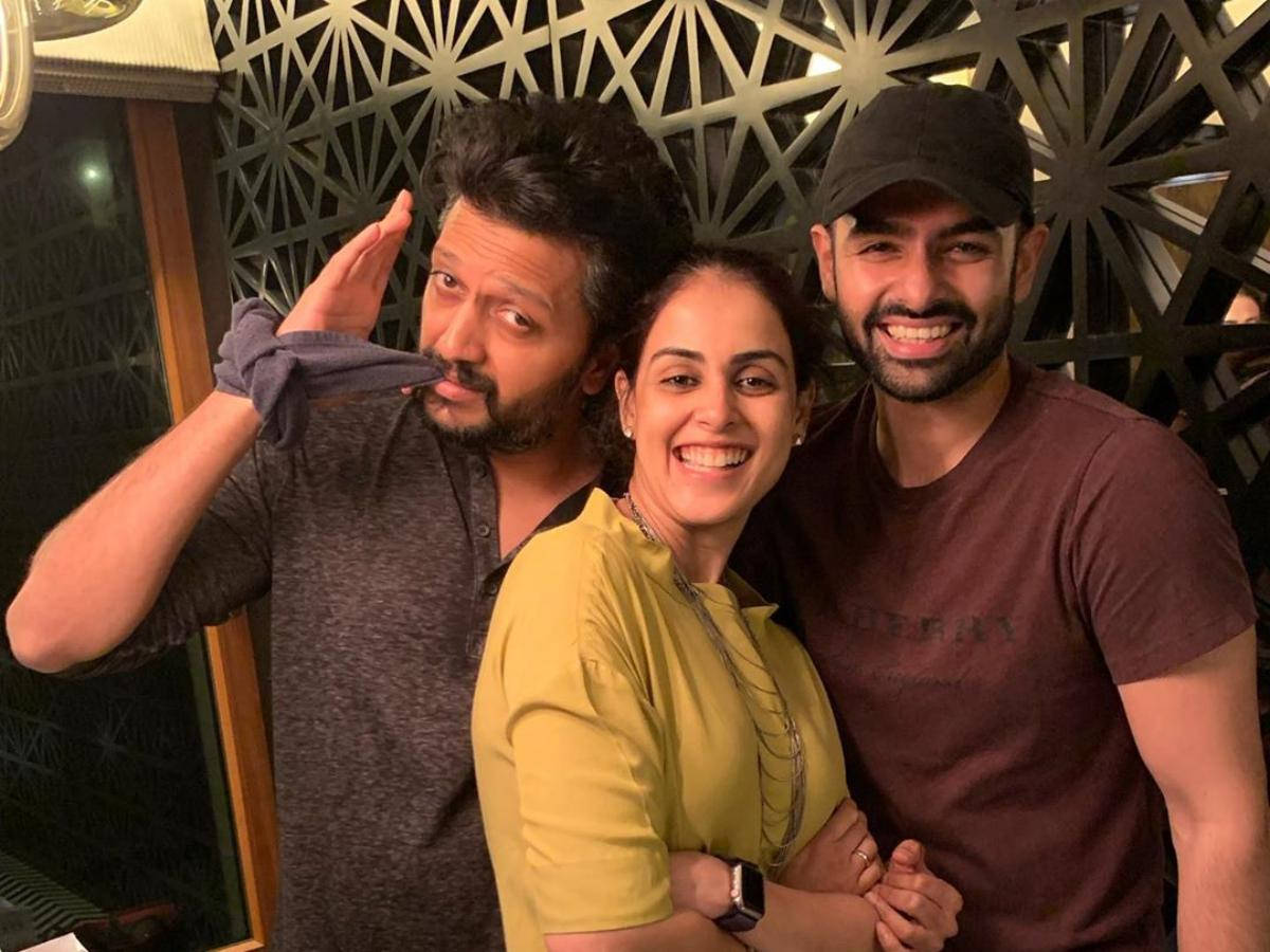 riteish deshmukh 桌布 壁紙 — 三位微笑的朋友在室內對著幾何圖案牆壁，在溫暖燈光下俏皮地擺姿勢。