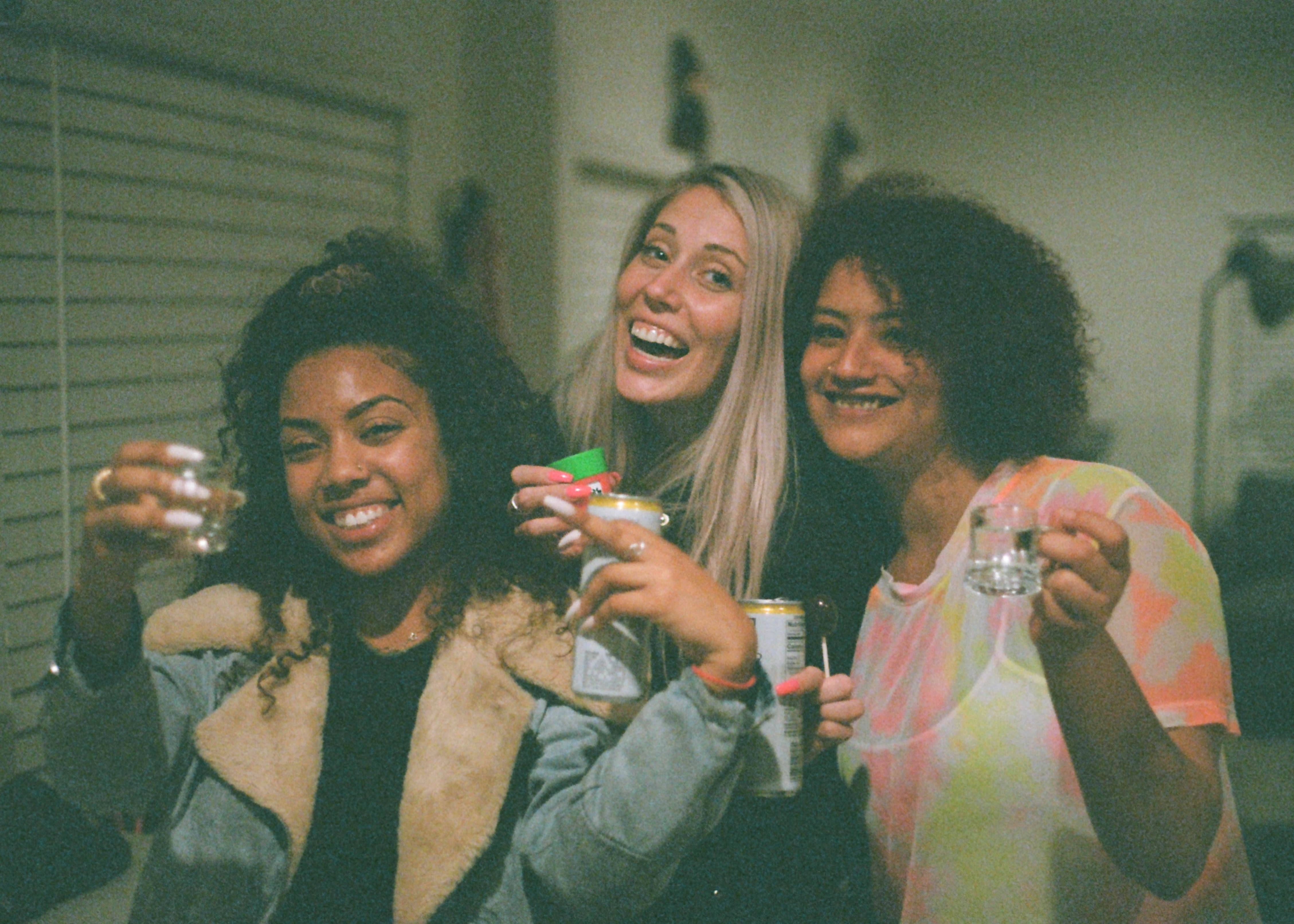 Bachelorette 桌布 壁紙 — 三位微笑的朋友在溫暖燈光的室內派對環境中舉杯暢飲。