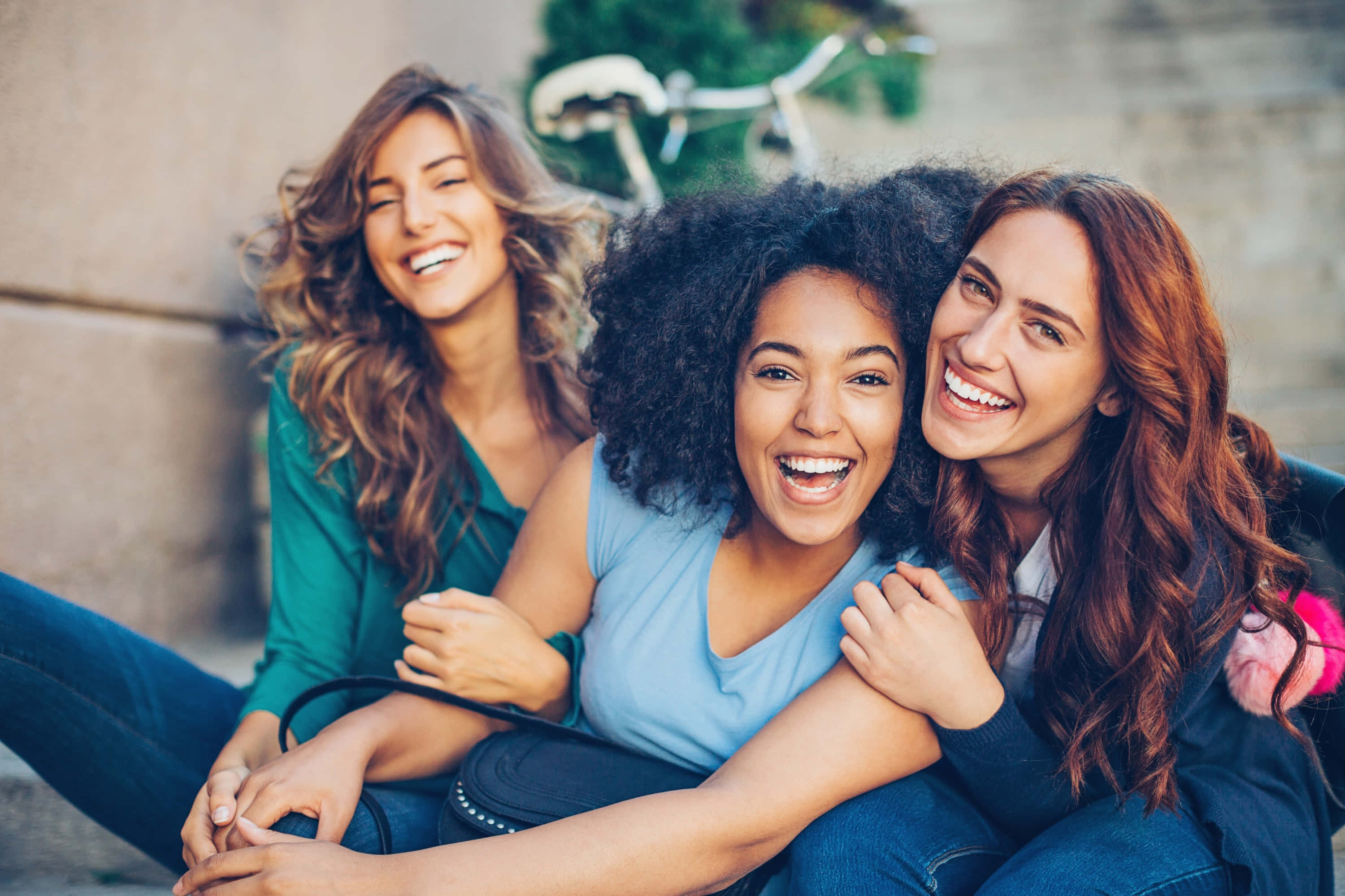 girls 桌布 壁紙 — 三位快樂的女性在戶外笑著，背景有一輛腳踏車。
