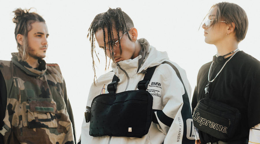 Chase Atlantic 桌布 壁紙 — 三位時尚年輕人並排站立，身穿品牌街頭服飾和斜背包，背景為亮白色。