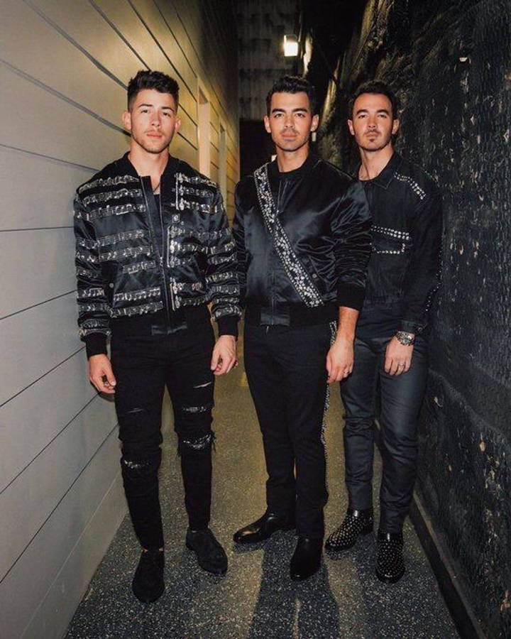 Jonas Brothers 桌布 壁紙 — 三位時尚男士身穿黑色亮片外套，自信地站在夜晚的狹窄小巷中。