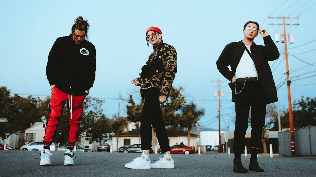 Chase Atlantic 桌布 壁紙 — 三位穿著時尚的男士在黃昏的郊區街道上自信地擺姿勢，背景有電線和停泊的汽車。