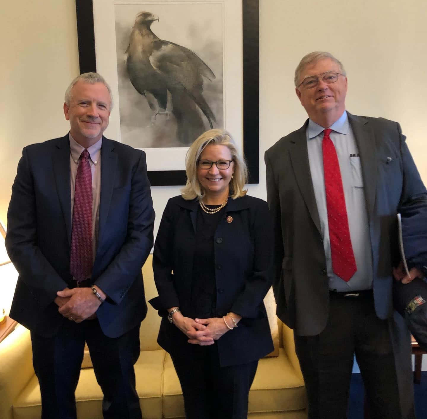 Celebrity 桌布 壁紙 — 三位穿著正式的人士在光線充足的辦公室裡微笑拍照，身後有一幅大型鷹藝術品。