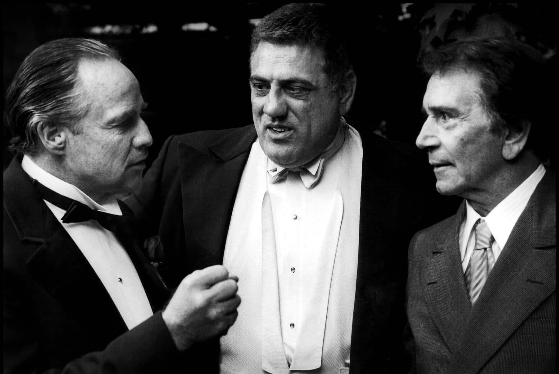 marlon brando 桌布 壁紙 — 三位穿著正裝的男子在昏暗的環境中進行緊張的對話。