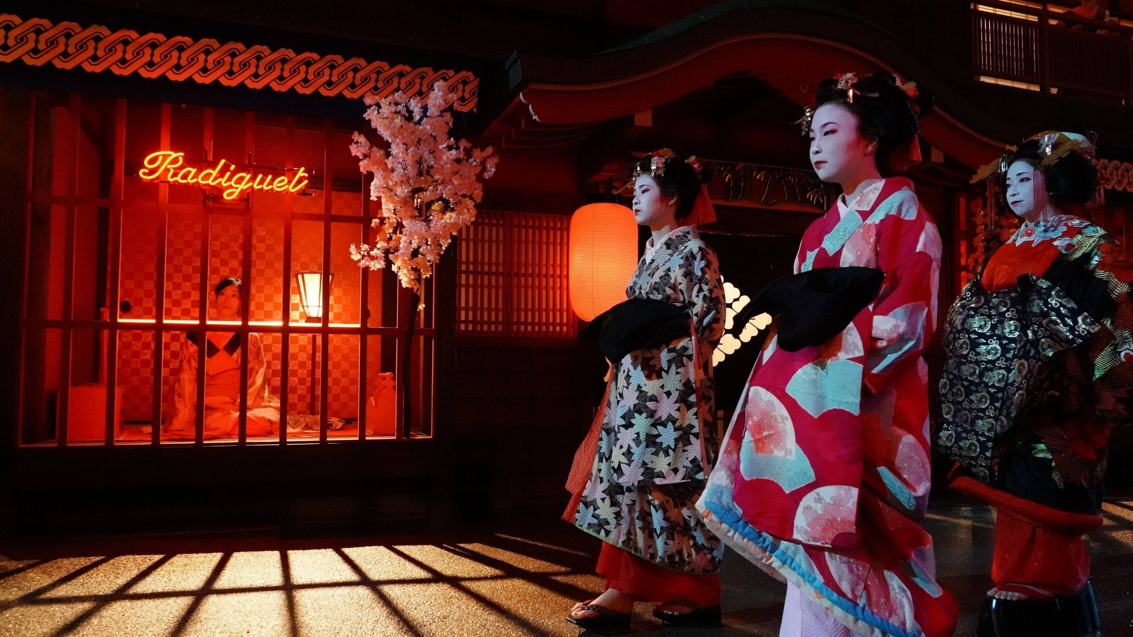 prisoners of the ghostland 桌布 壁紙 — 三位穿著鮮豔和服的藝妓，在黃昏時分站在一座霓虹燈閃爍的傳統日本建築前。