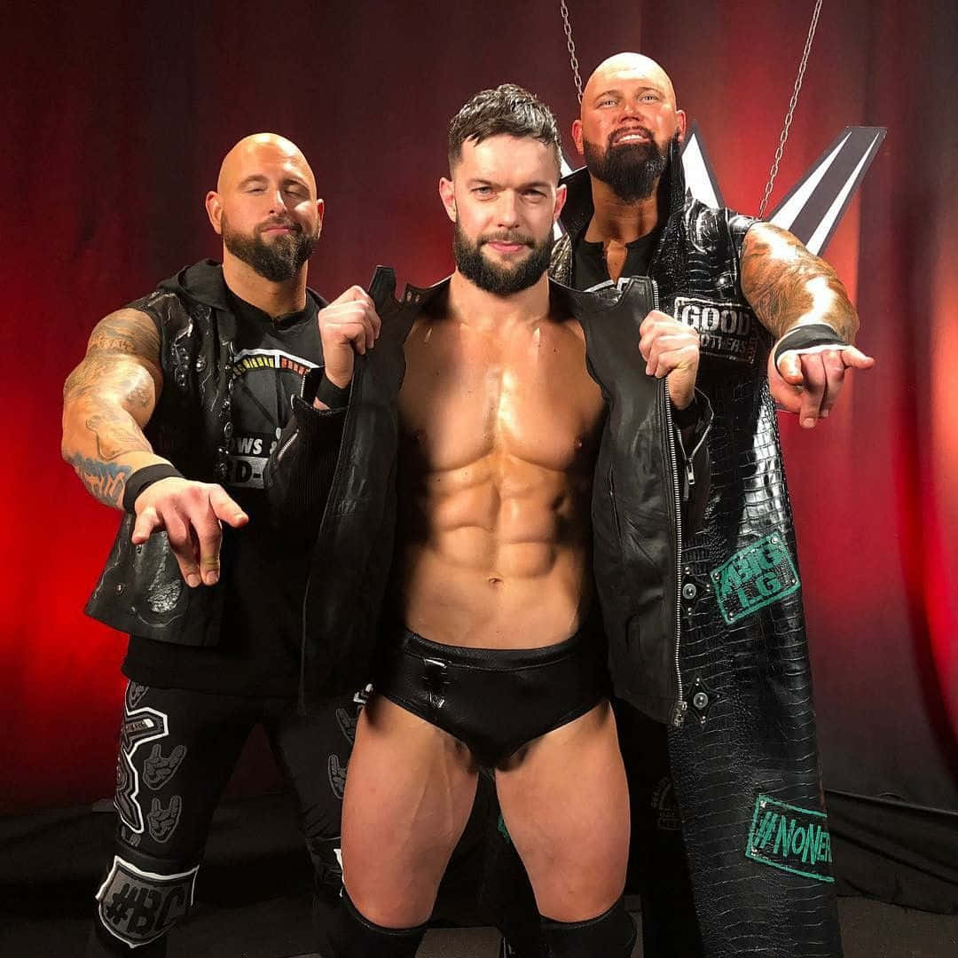 WWE 桌布 壁紙 — 三位肌肉發達的摔角手穿著黑色皮革裝備，在戲劇性的紅色帷幕背景下自信地擺姿勢。