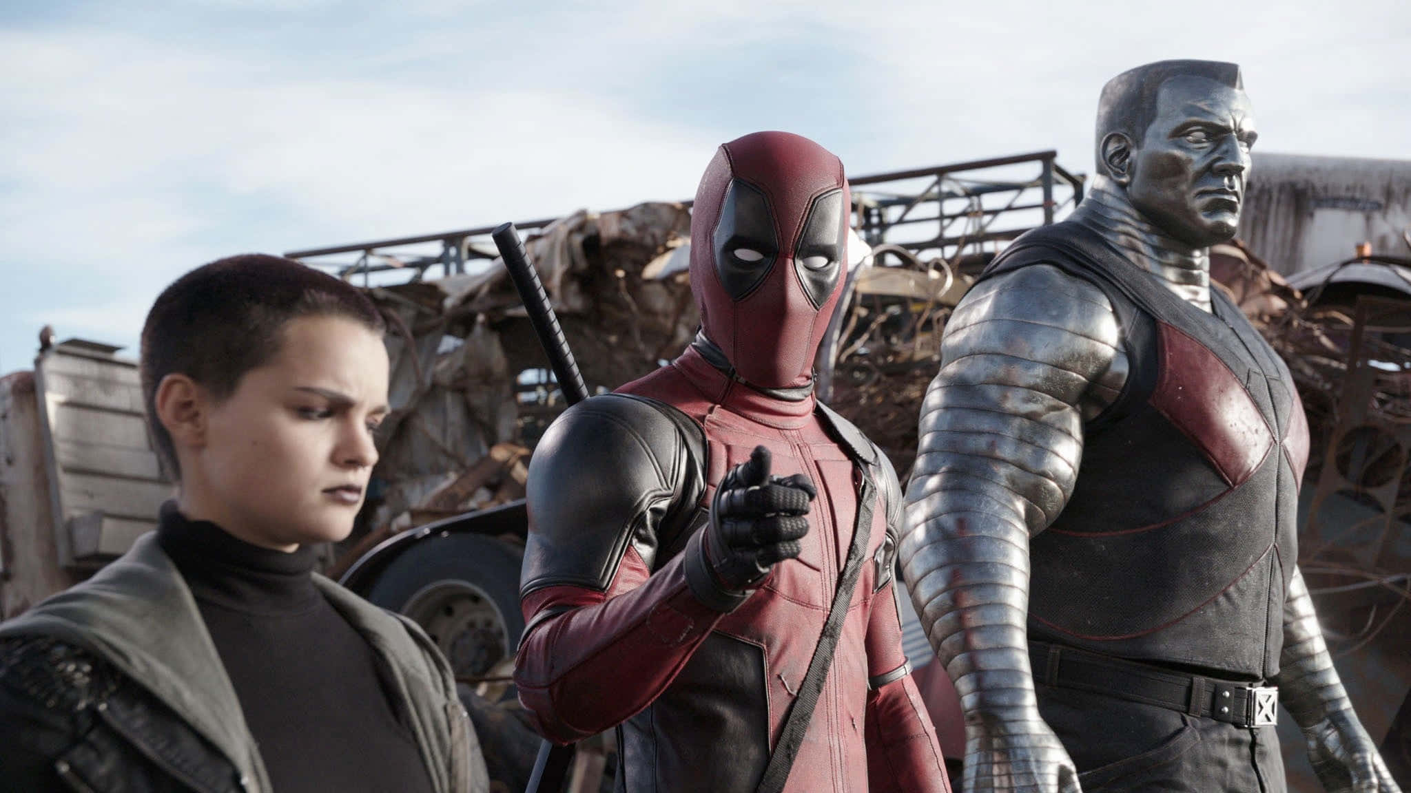 Deadpool And Negasonic Teenage Warhead 桌布 壁紙 — 三位超級英雄站在垃圾場，身穿紅色的死侍指向前方，旁邊有一個金屬人物和一個穿深色衣服的女人。