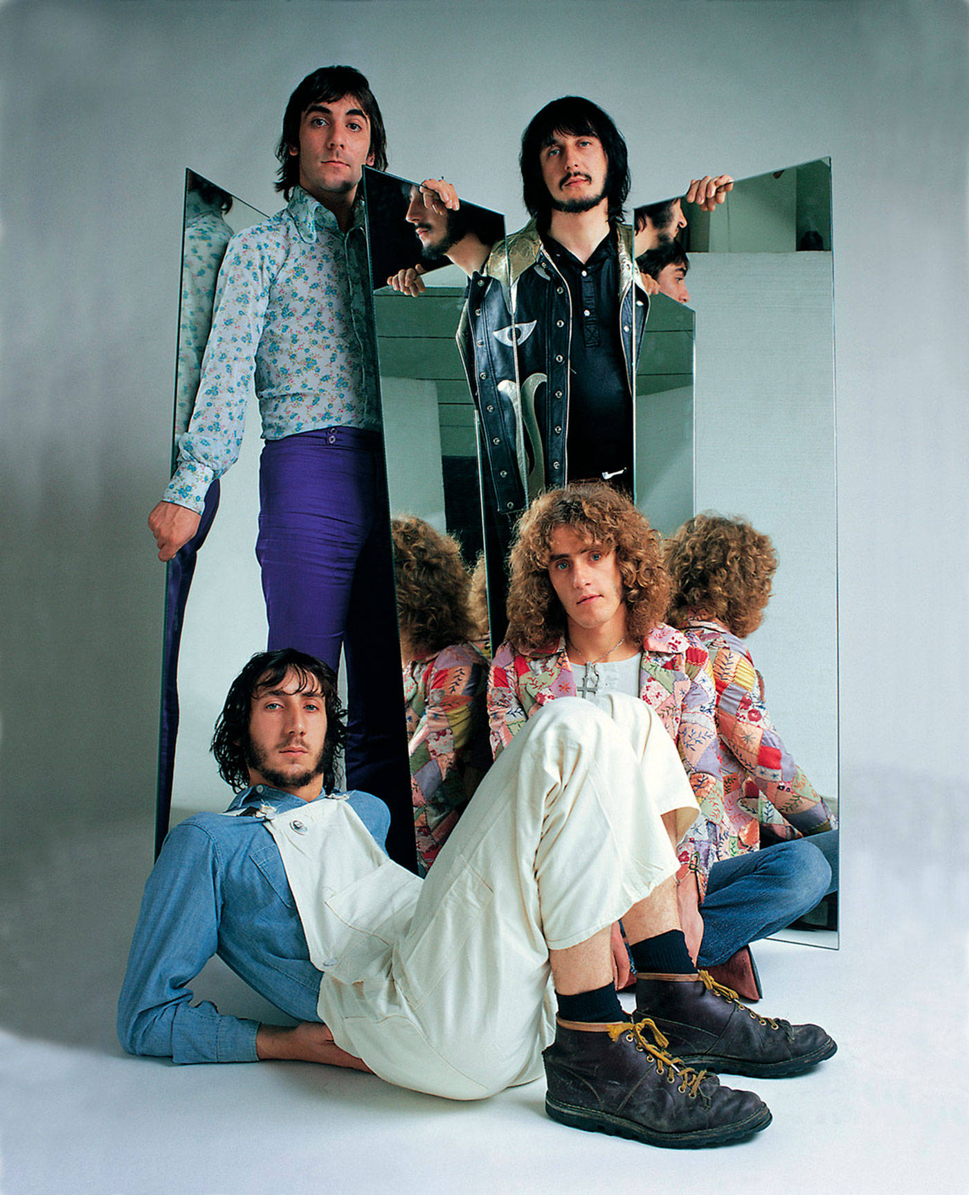 Rock 桌布 壁紙 — 三位身穿1970年代時尚的男士，與破碎的鏡子擺姿勢，鏡子反射出他們不拘一格的服裝和富有表現力的面孔。