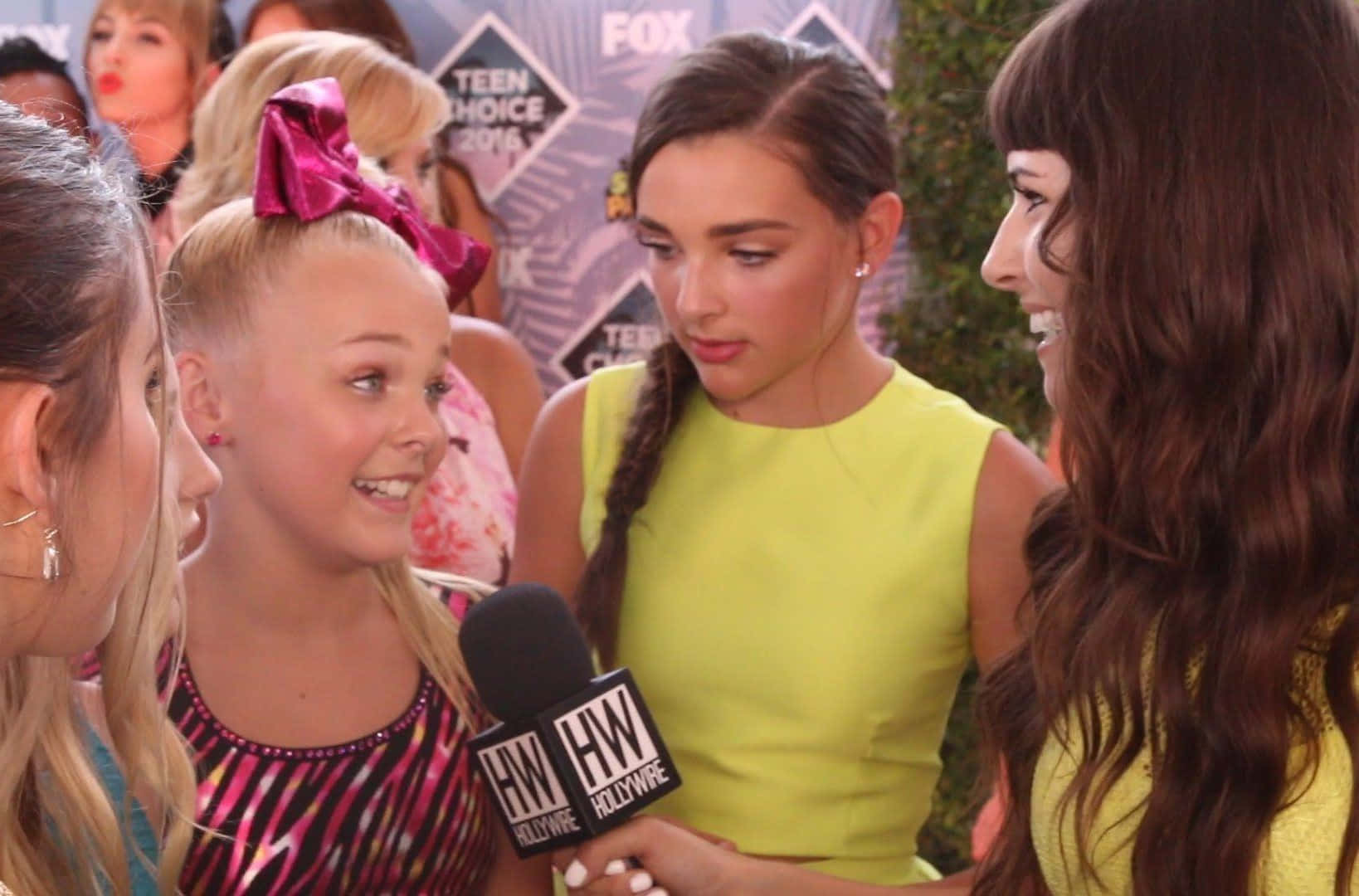 JoJo Siwa 桌布 壁紙 — 三位身穿亮麗服裝的年輕女性在Teen Choice Awards紅地毯採訪中，用HollywoodWire麥克風聊天。
