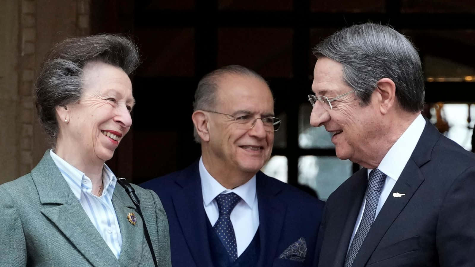 Cyprus 桌布 壁紙 — 三位身穿正式服裝的顯要人物在戶外外交會議中分享溫暖真誠的笑聲。