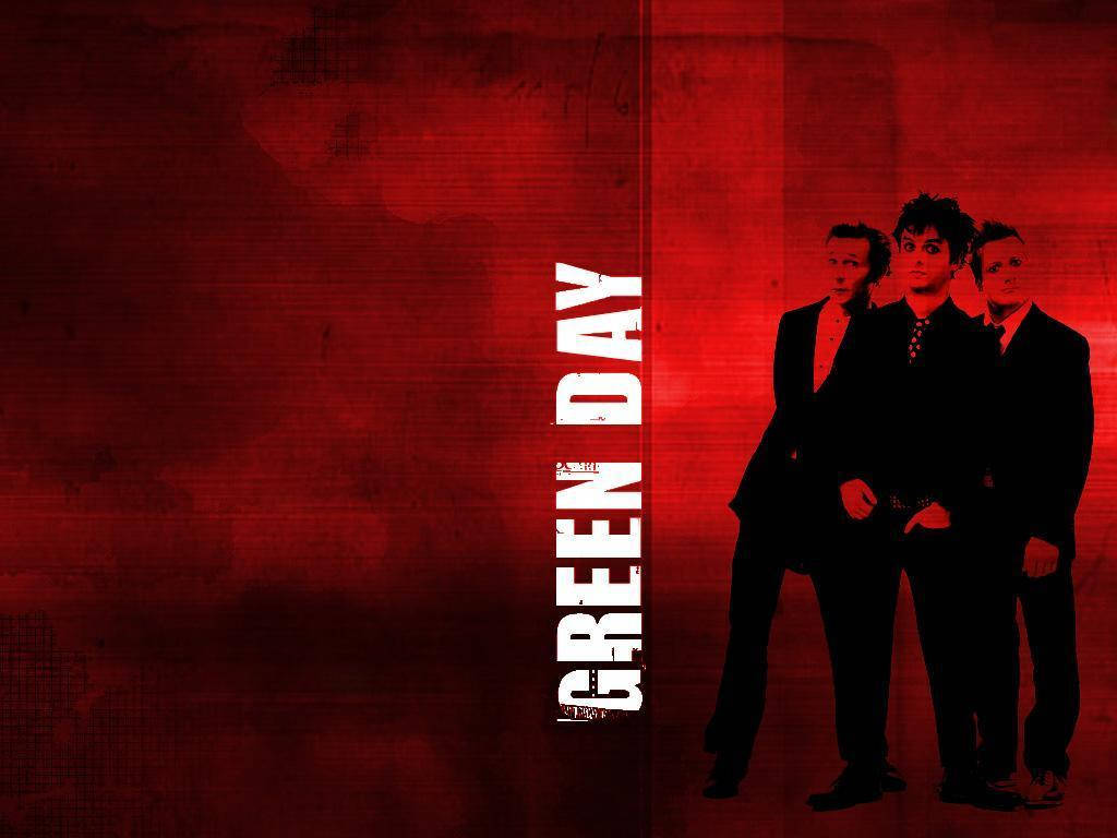 Green Day 桌布 壁紙 — 三位身穿深色西裝的樂團成員站在有紋理的紅色背景前，背景上有粗體白色垂直文字寫著「GREEN DAY」。