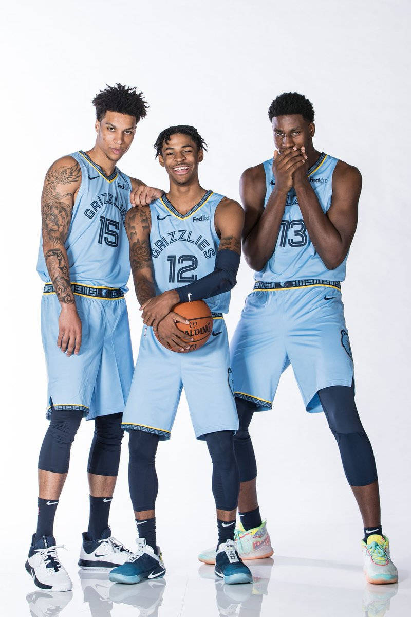 Grizzlies 桌布 壁紙 — 三位身穿淺藍色球衣的曼菲斯灰熊隊籃球運動員面帶微笑，在白色攝影棚背景前自信地擺姿勢。
