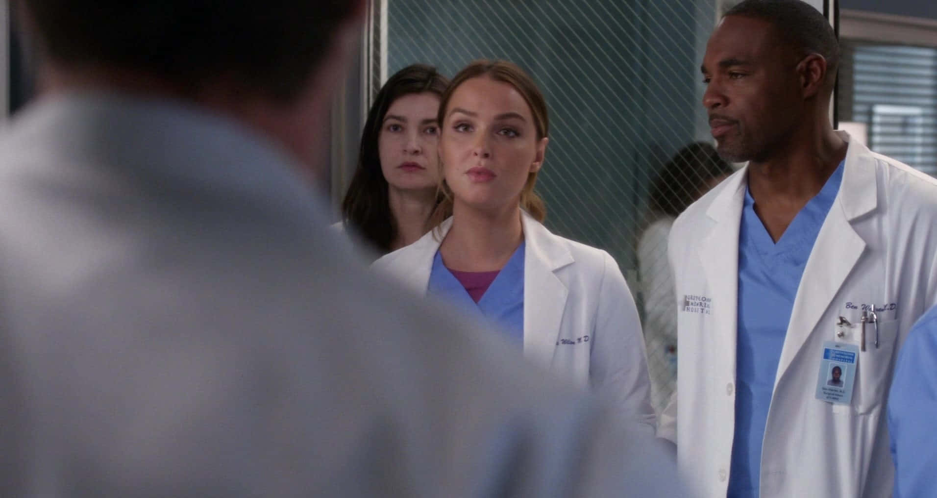 Grey's Anatomy 桌布 壁紙 — 三位身穿白袍的醫護人員站在醫院走廊，表情嚴肅。
