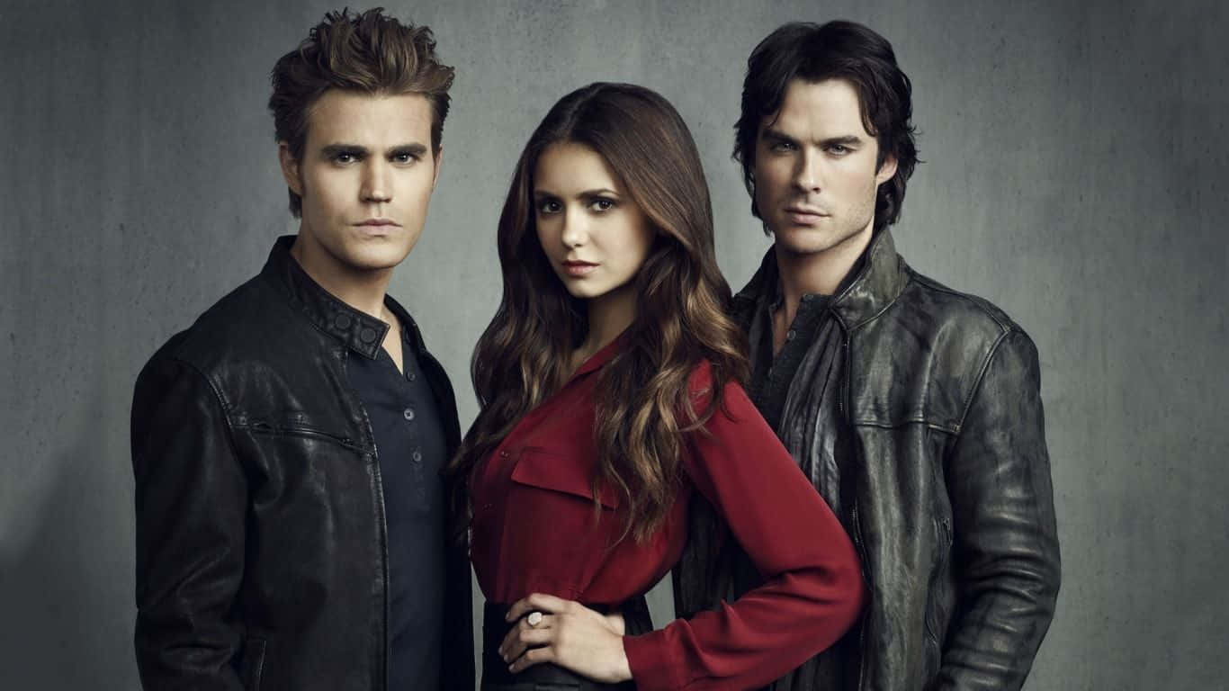 Vampire Diaries Desktop 桌布 壁紙 — 三位身穿皮夾克和紅色襯衫的嚴肅演員在灰色紋理牆前擺姿勢。