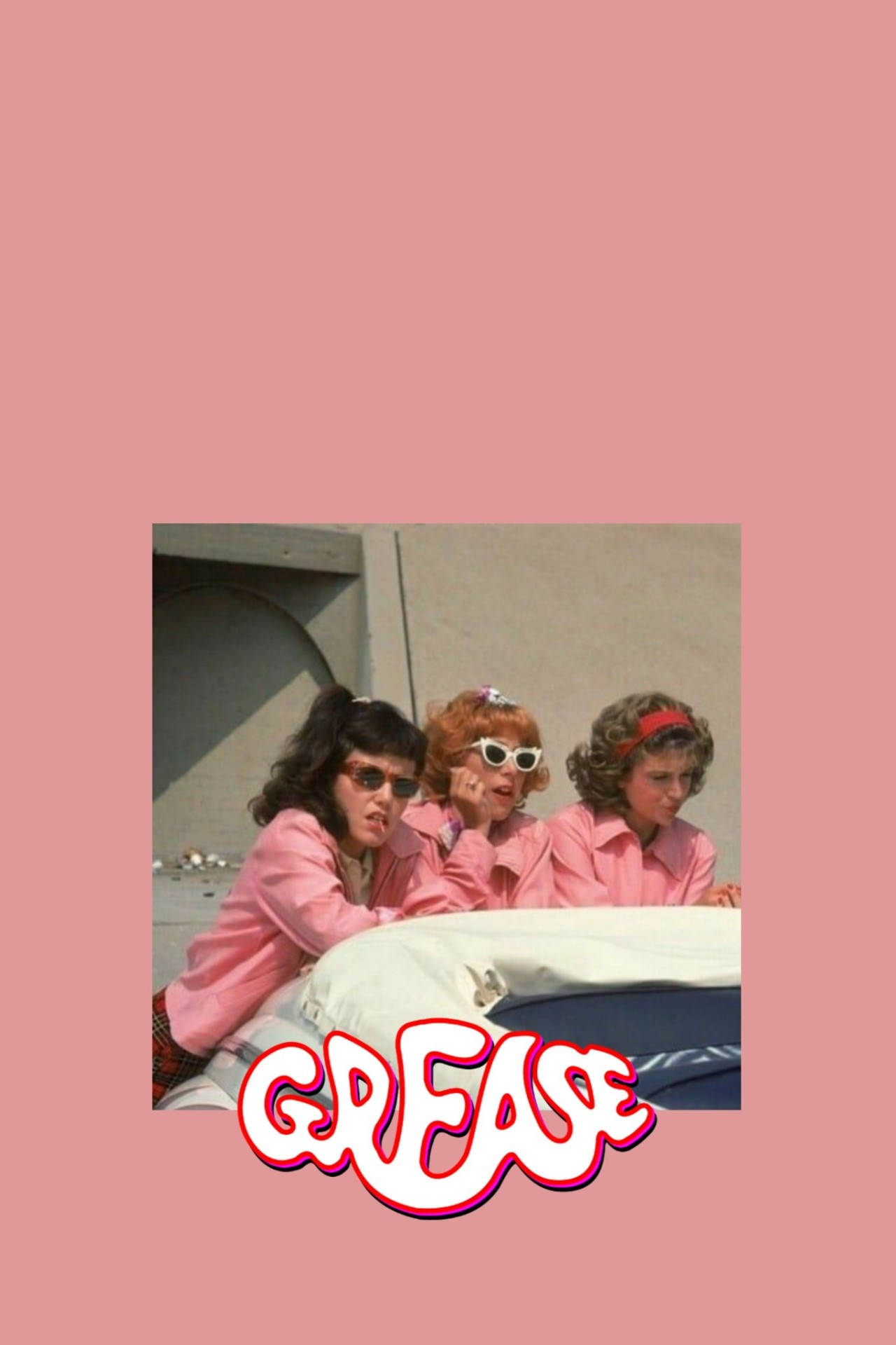 Grease 桌布 壁紙 — 三位身穿粉紅色外套和太陽眼鏡的女性，靠在一輛帶有 'GREASE' 標誌的汽車上，背景為純粉紅色。