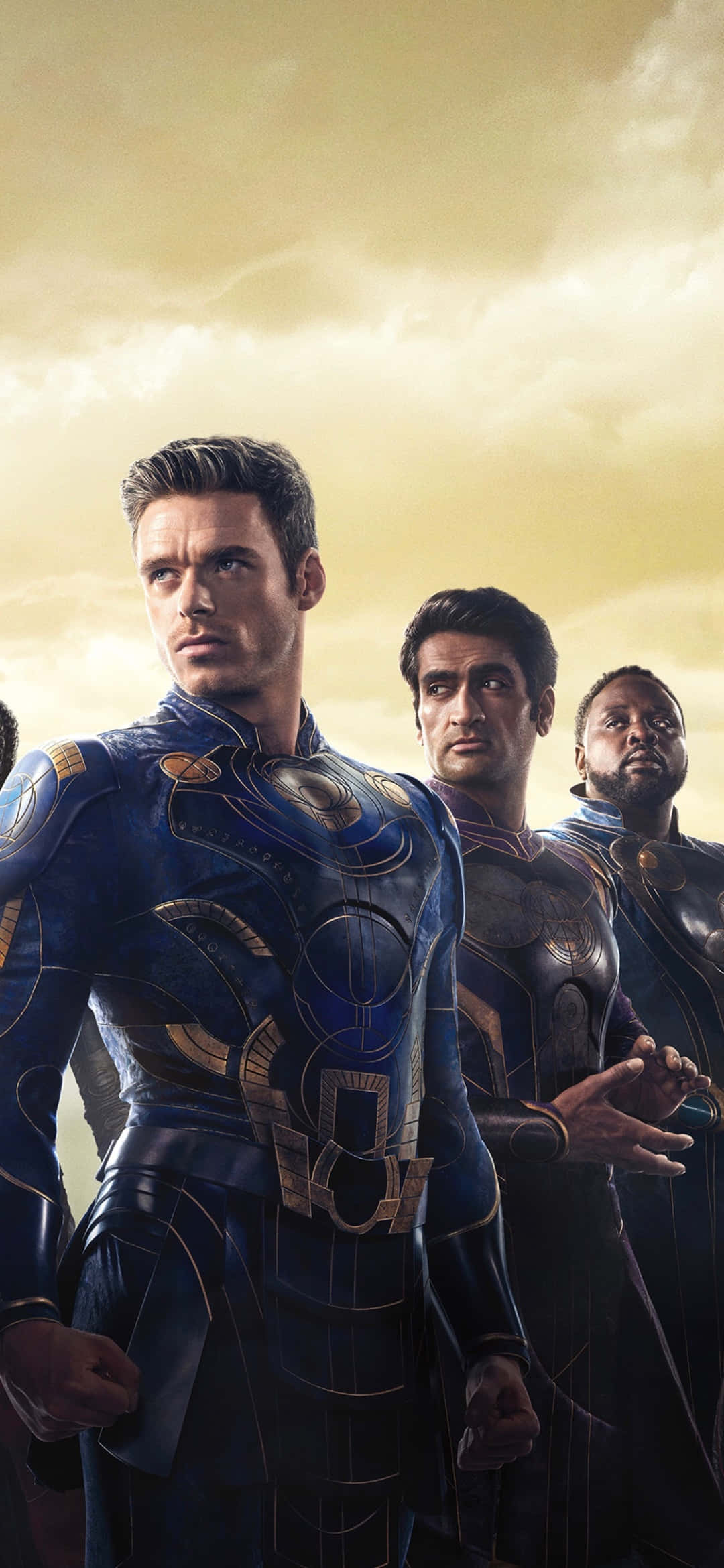 Eternals Movie 桌布 壁紙 — 三位身穿精細藍金鎧甲的超級英雄，在金色多雲的天空下堅定站立。
