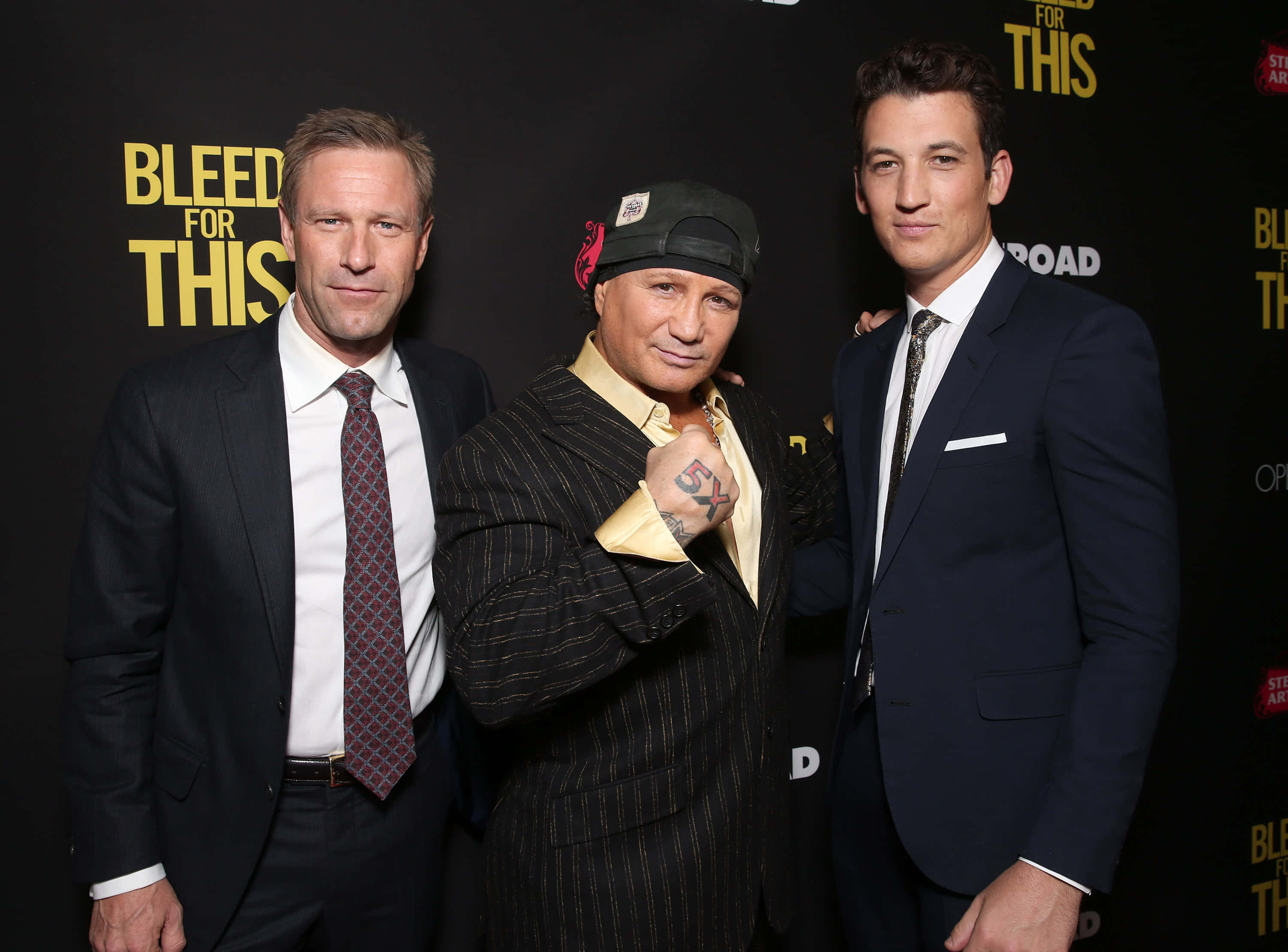 actor 桌布 壁紙 — 三位身穿西裝的男子在《Bleed for This》電影首映會上自信地擺姿勢，背景為大膽的黃色文字。