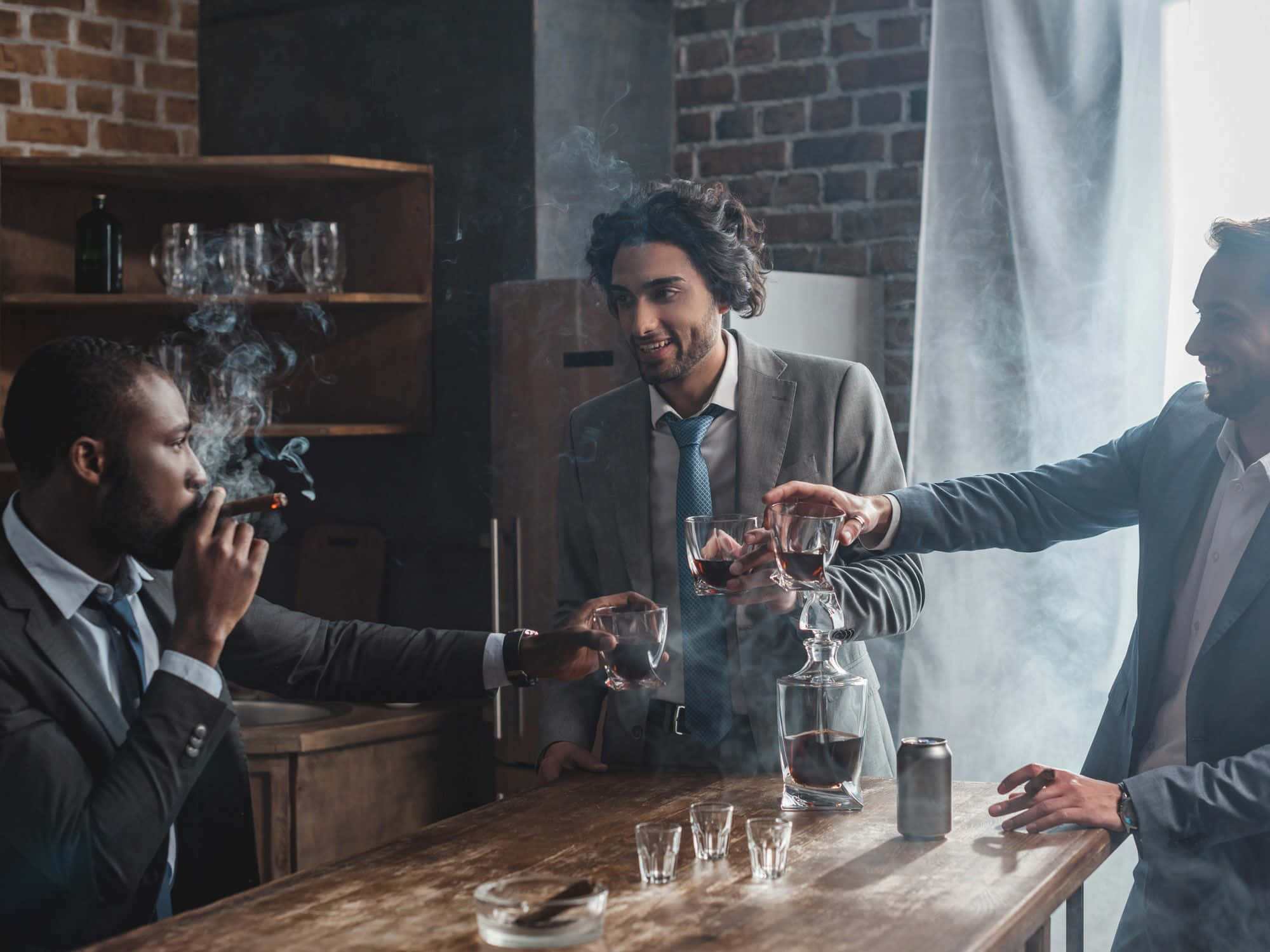 Party 桌布 壁紙 — 三位身穿西裝的男子在煙霧瀰漫的酒吧中，以紅酒杯敬酒，背景是磚牆和木製吧檯。