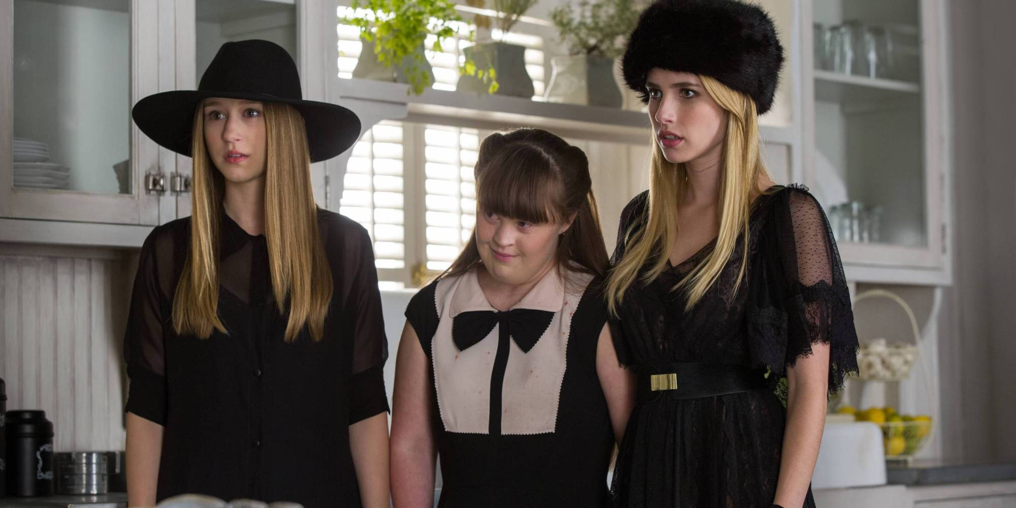 American Horror Story 桌布 壁紙 — 三位身穿黑色服裝和帽子的女性站在一個明亮的廚房裡，廚房裡有白色櫥櫃和植物。